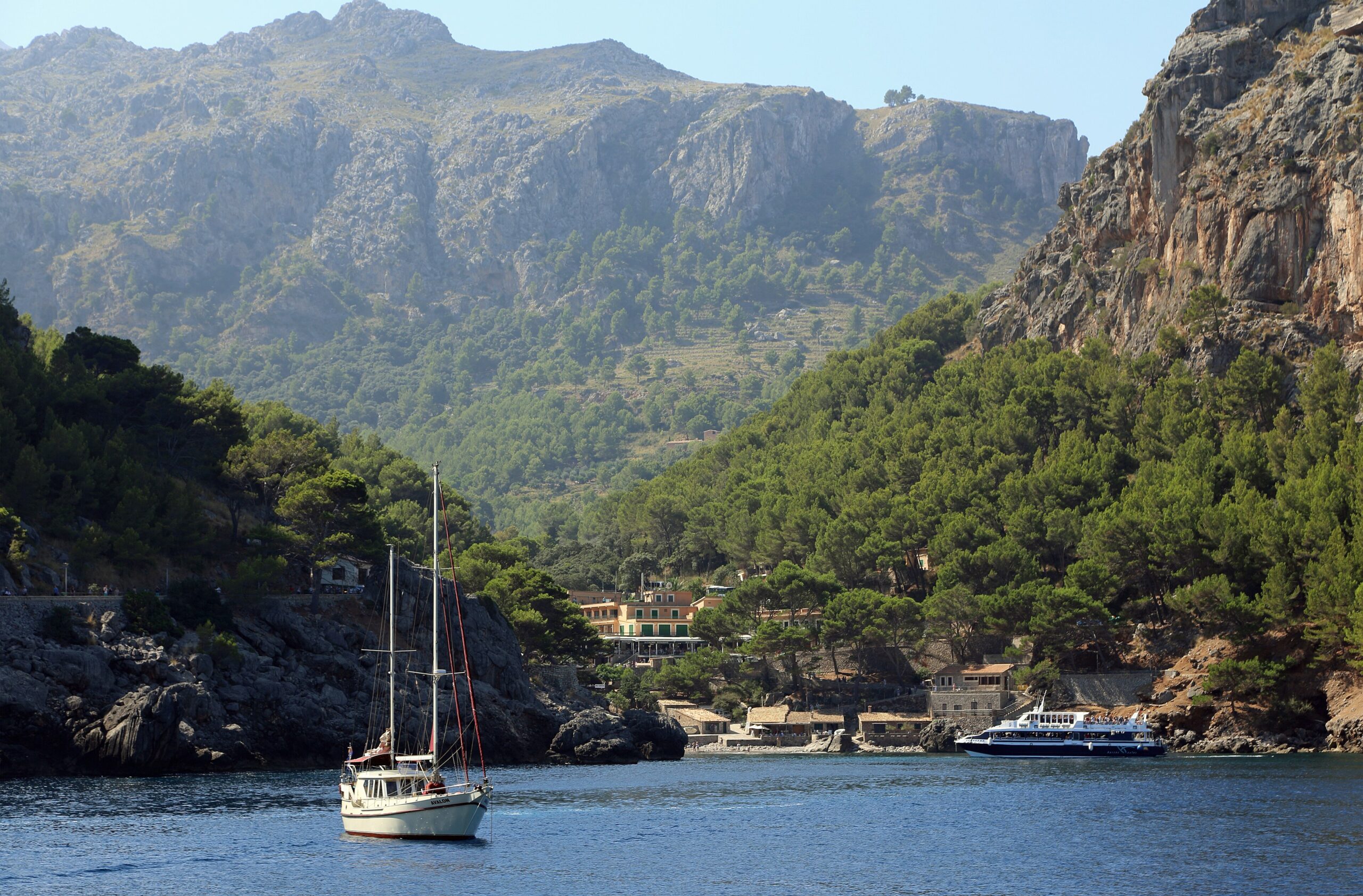 Excursieboot en zeilboot in de baai van Sa Calobra onder de bergen van de Serra de Tramuntana