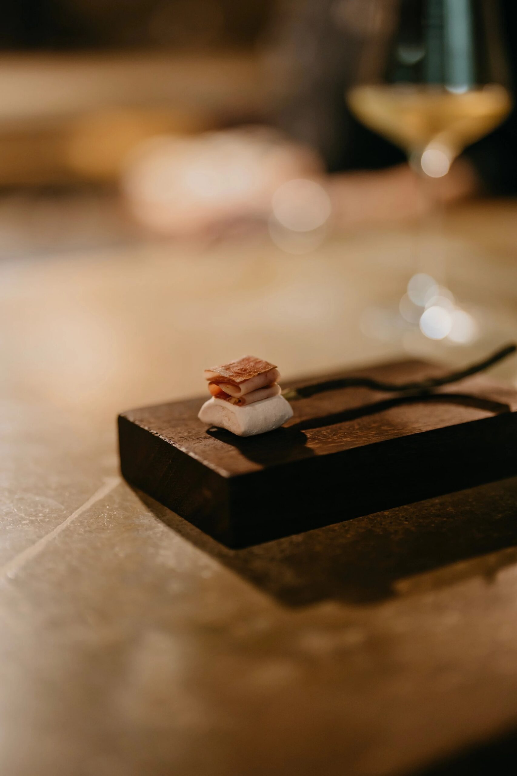 Brut in Llubí: één zitting per avond in een oude houtloods 3 Klein hapje met caviar en marshmallow op een donker houten blokje aan de bar van Brut in Llubí