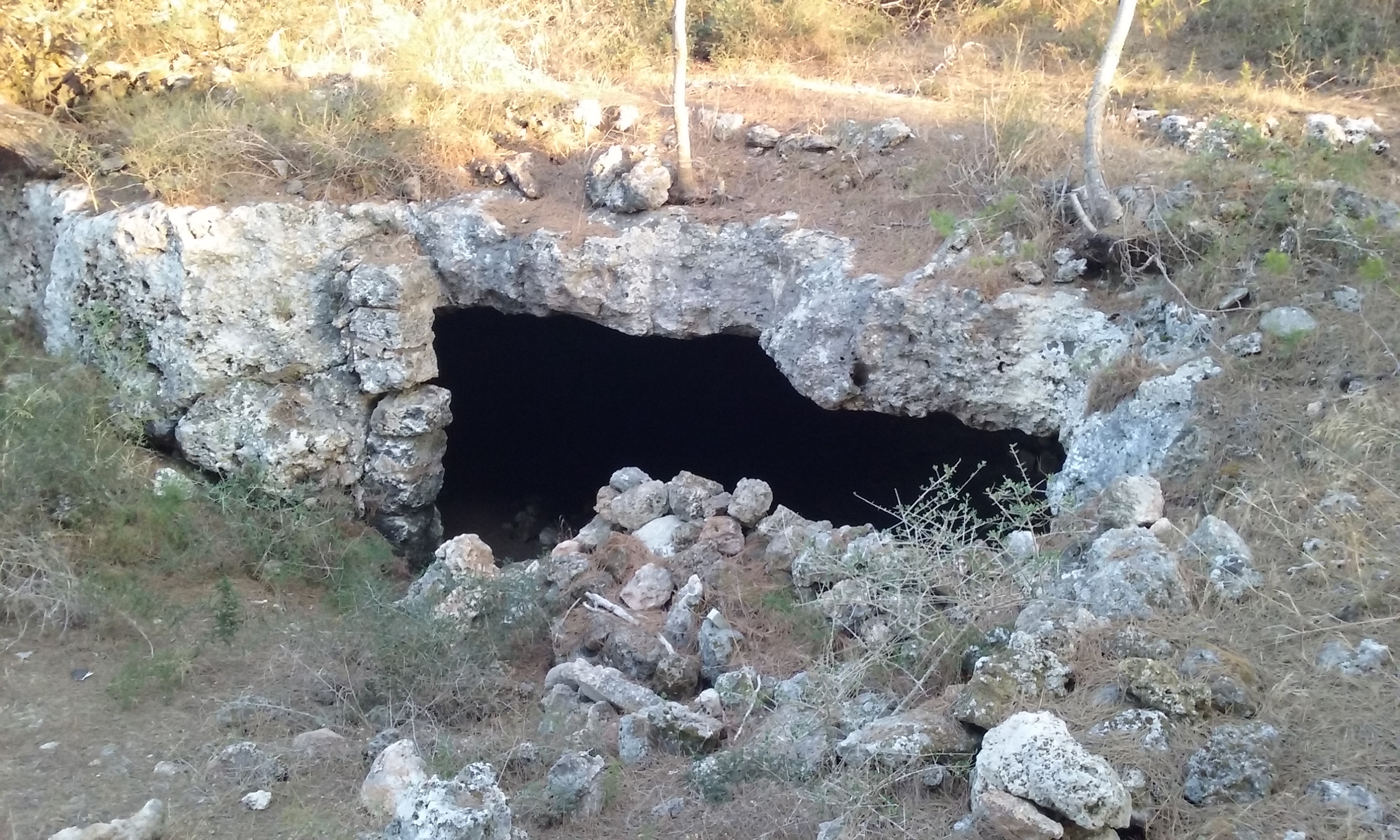 Cala Blanca Menorca: witte zandbaai met zonsondergang bij Ciutadella 6 De in de rots uitgehakte ingang van een hypogeum van Parella Nova bij Cala Blanca