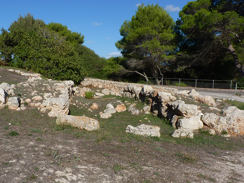 Cala Blanca Menorca: witte zandbaai met zonsondergang bij Ciutadella 3 De resten van de prehistorische naveta d'habitacio van Cala Blanca, een paar lagen stenen muur langs de weg