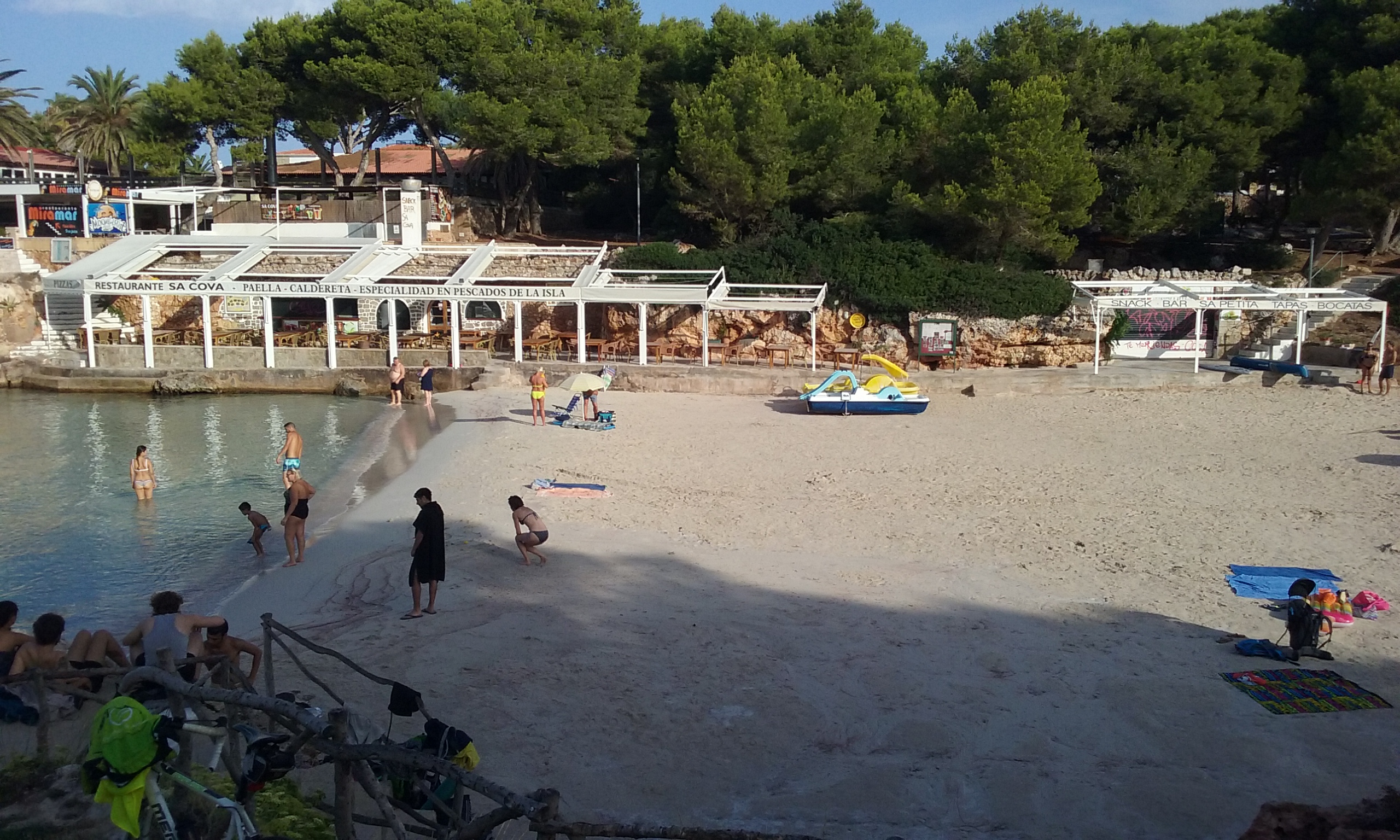 Cala Blanca Menorca: witte zandbaai met zonsondergang bij Ciutadella 4 Het zand van Cala Blanca met de witte terrassen van Restaurante Sa Cova en de snackbar op de rotsrand erachter