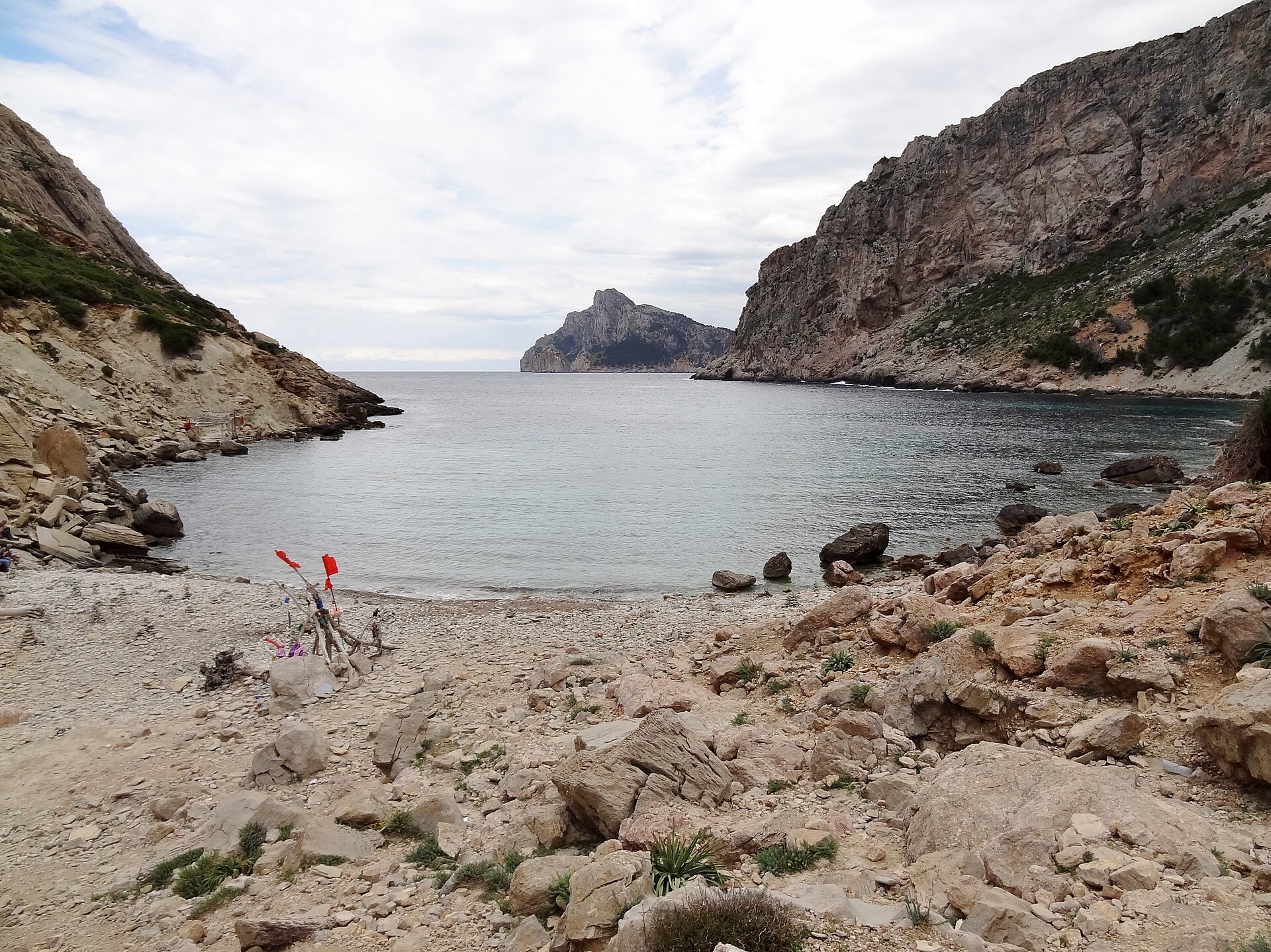 Cala Bóquer Mallorca: de baai aan het eind van het vogeldal 4 De baai van Cala Bóquer met de rotsige oever, drijfhout met rode vlaggetjes en de kaap in de verte