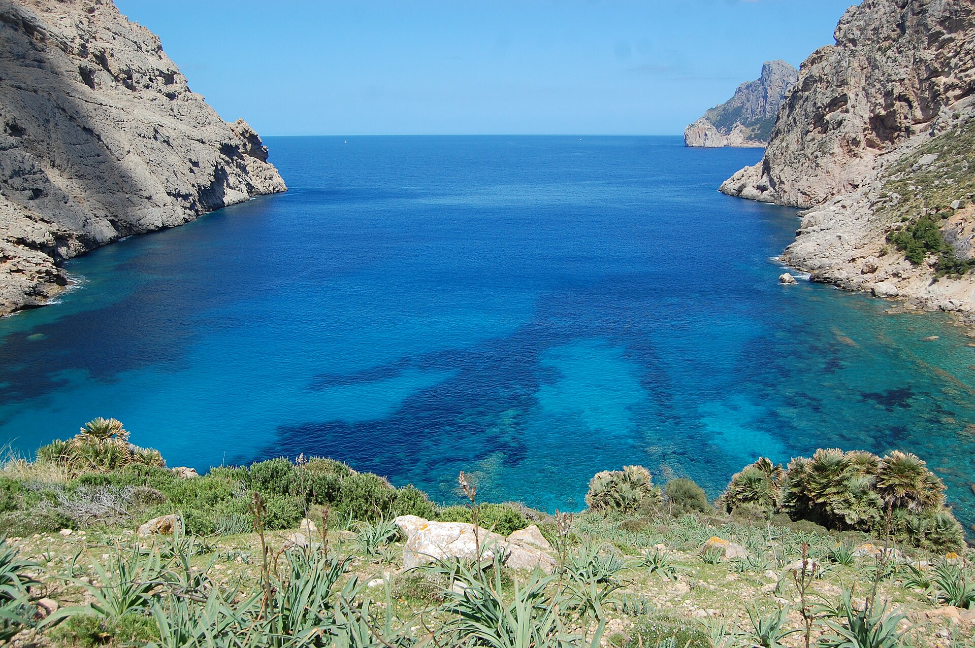 Cala Bóquer Mallorca: de baai aan het eind van het vogeldal 1 Cala Bóquer van bovenaf gezien, met diepblauw water tussen twee steile rotswanden en dwergpalmen op de voorgrond