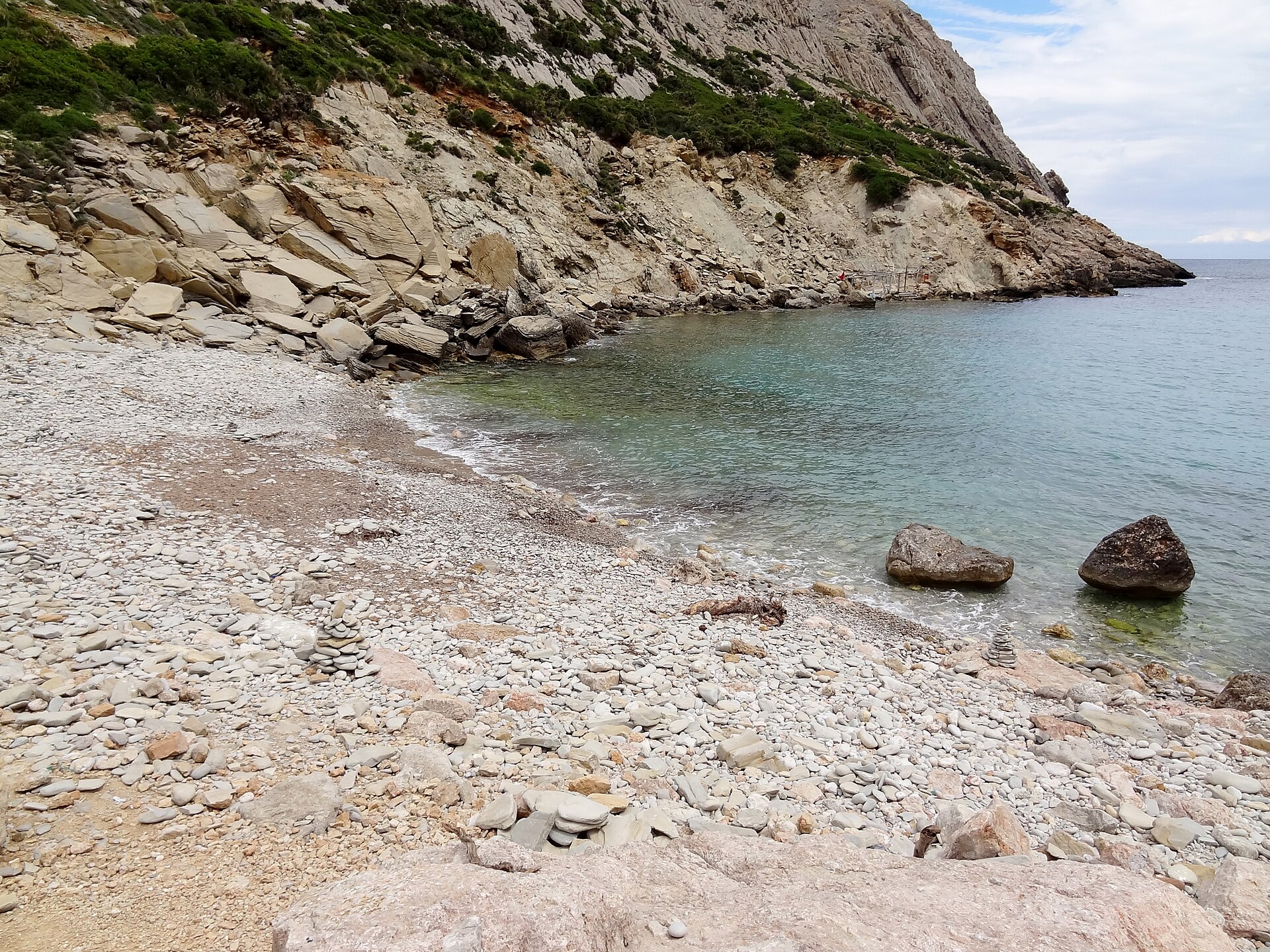Cala Bóquer Mallorca: de baai aan het eind van het vogeldal 6 De gelaagde rotswand boven het kiezelstrand van Cala Bóquer, met helder groen water ervoor