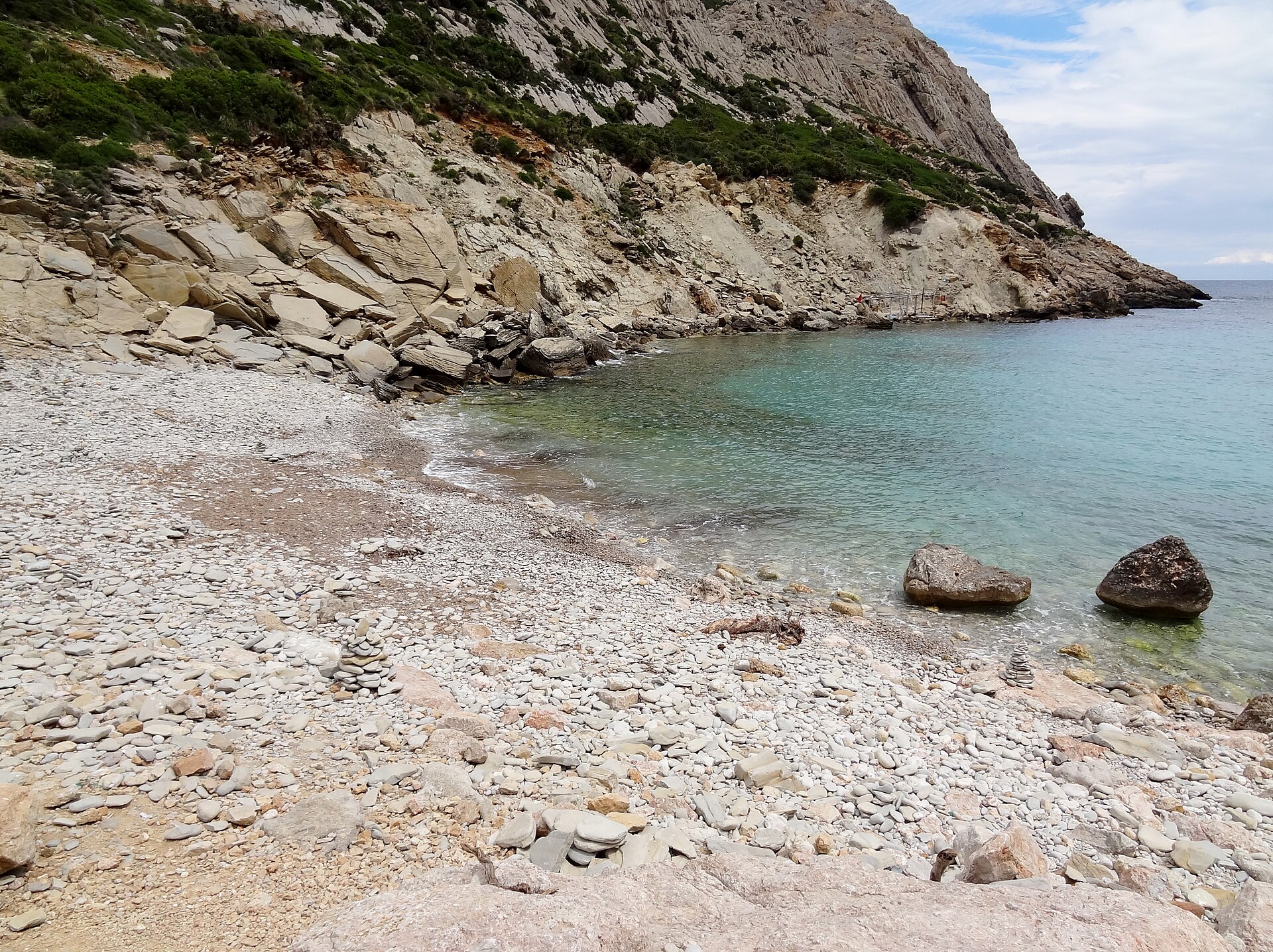 Cala Bóquer Mallorca: de baai aan het eind van het vogeldal 2 De strook platte witte kiezels van Cala Bóquer met steenstapeltjes, helder groen water en de rotswand erachter