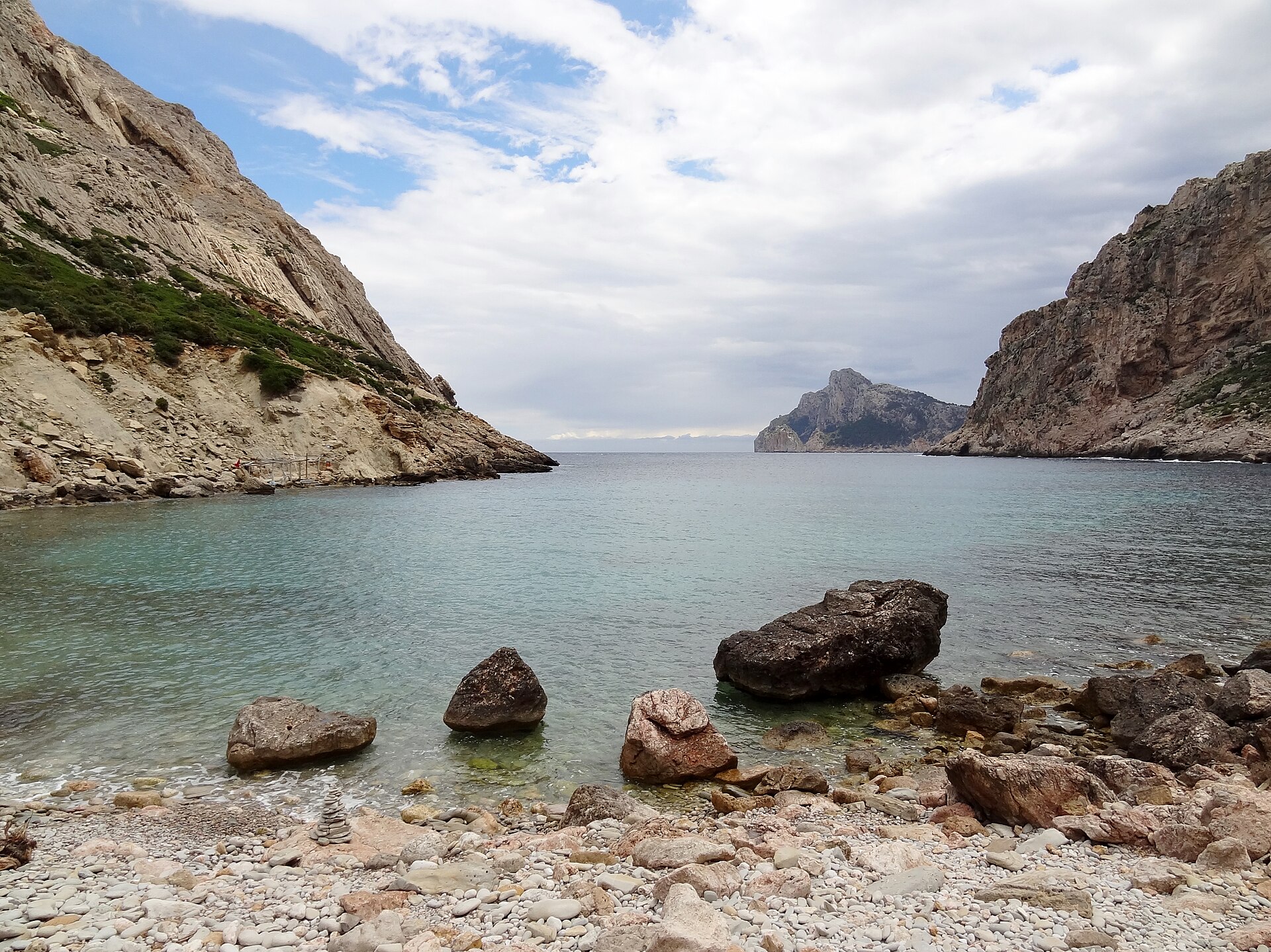 Cala Bóquer Mallorca: de baai aan het eind van het vogeldal 3 Cala Bóquer vanaf de waterlijn gezien, met rotsblokken in het ondiepe water en de twee rotswanden die naar zee openstaan