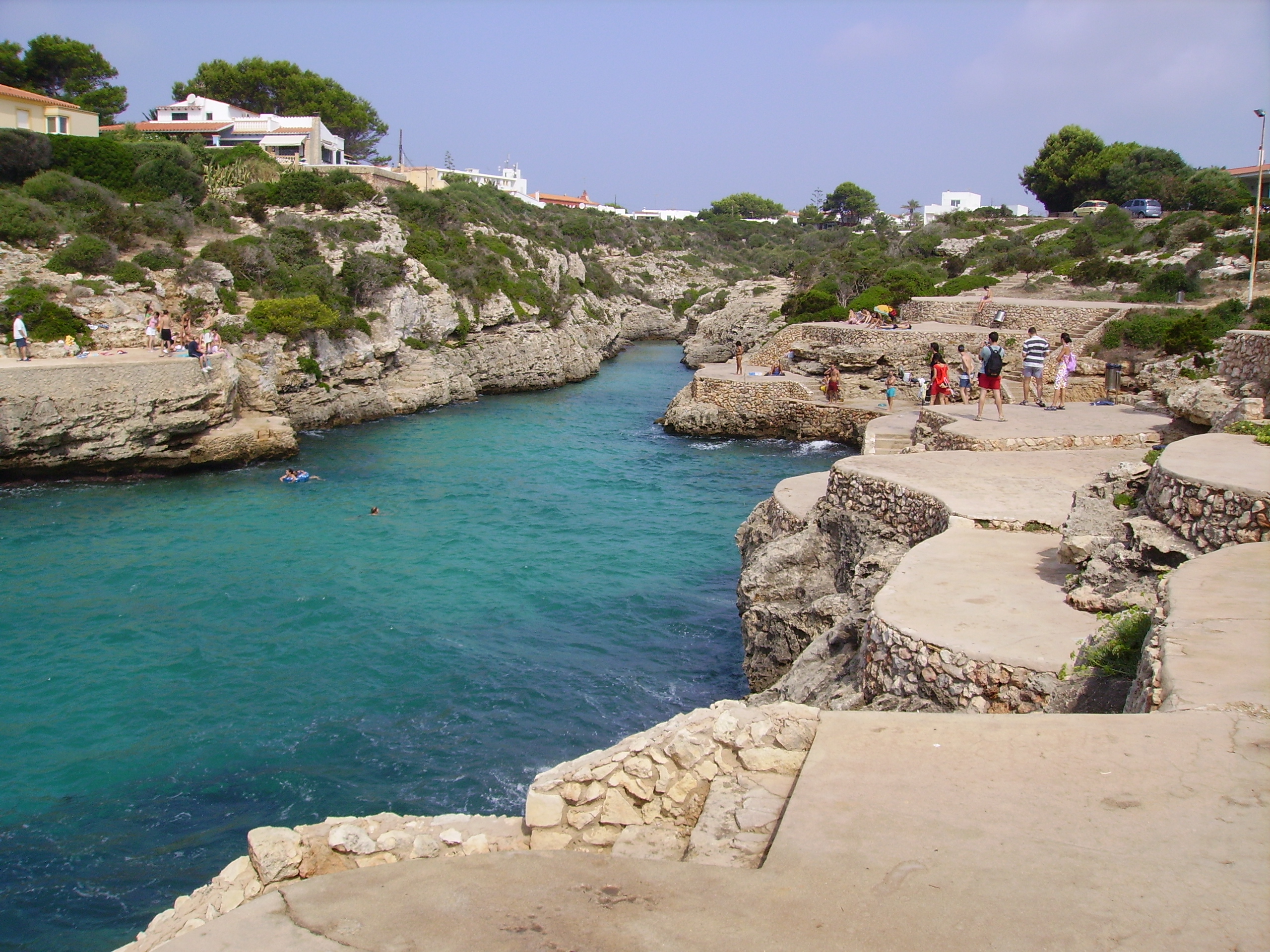 Cala en Blanes Menorca: de kloofbaai bij Ciutadella, met Cala en Forcat en Los Delfines 4 De betonnen terrassen en trappen van Cala en Brut boven het turquoise water
