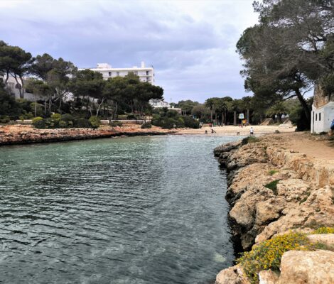 De smalle inham van Cala en Blanes met turquoise water, rotsranden en het zandstrand achter in de kloof