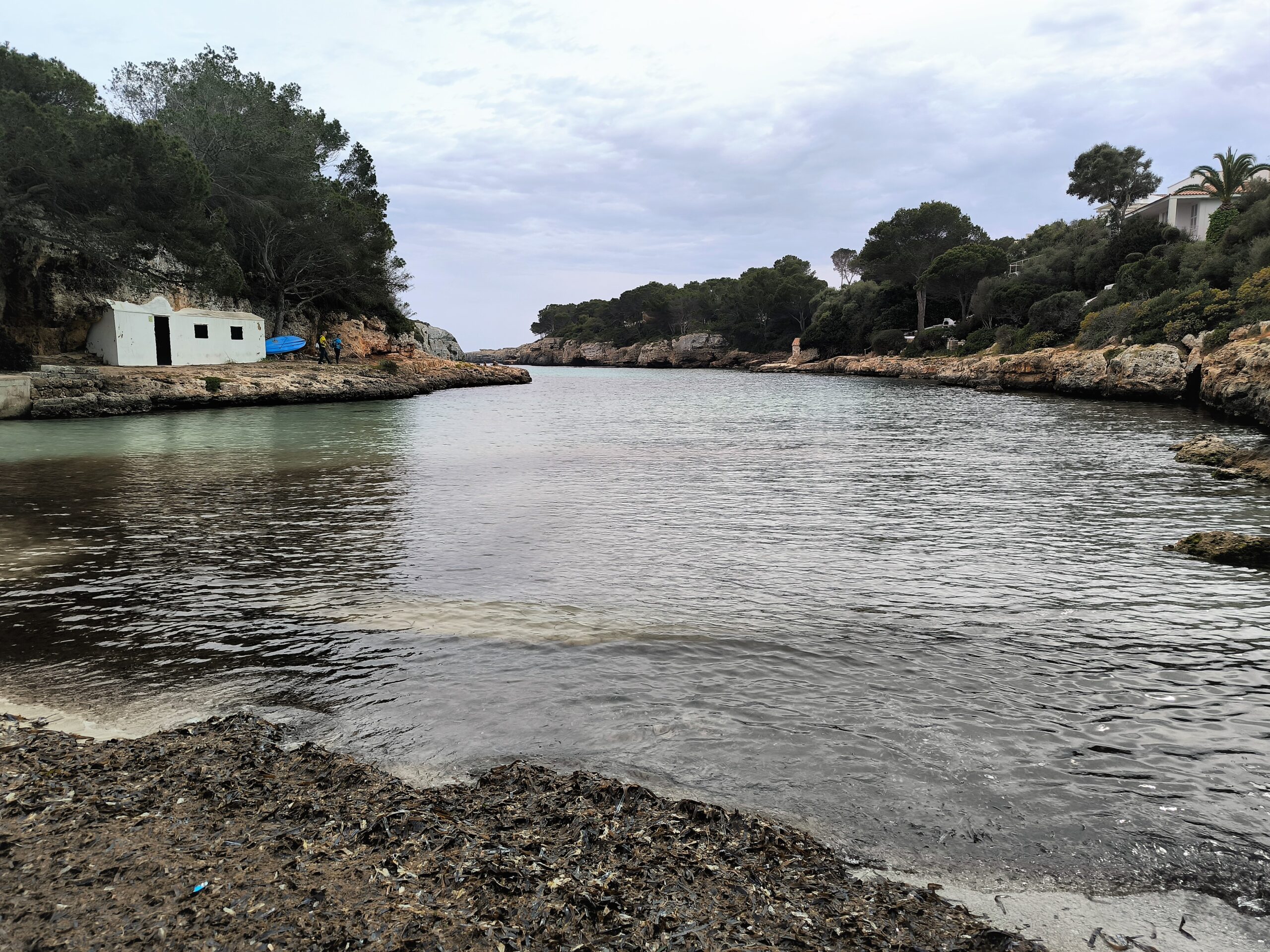 Cala en Blanes Menorca: de kloofbaai bij Ciutadella, met Cala en Forcat en Los Delfines 8 Het strand van Cala en Blanes buiten het seizoen, met het witte botenhuis en pijnbomen aan de waterkant