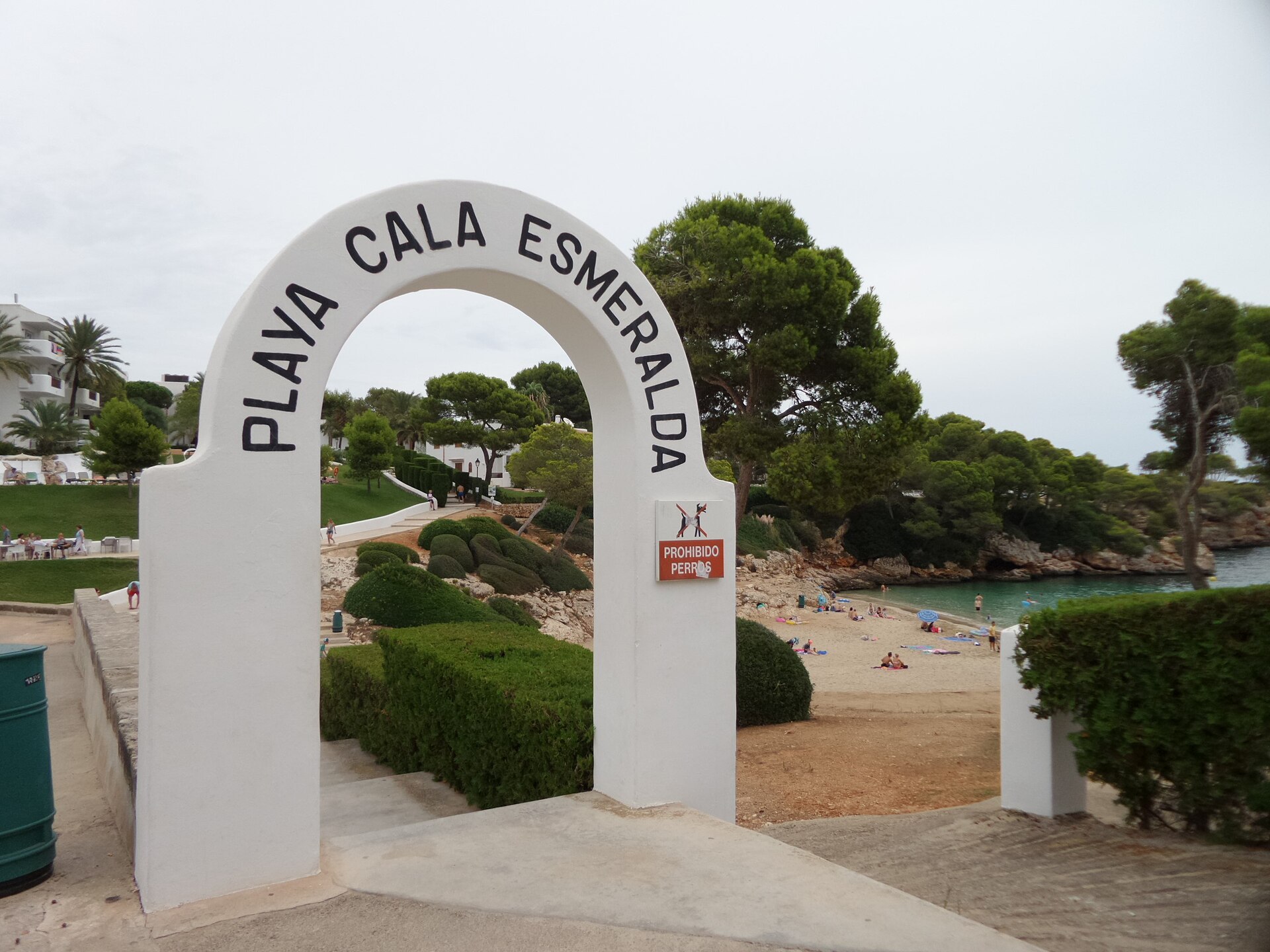 De witgekalkte poort met het opschrift Playa Cala Esmeralda en daarnaast een rood bord met prohibido perros