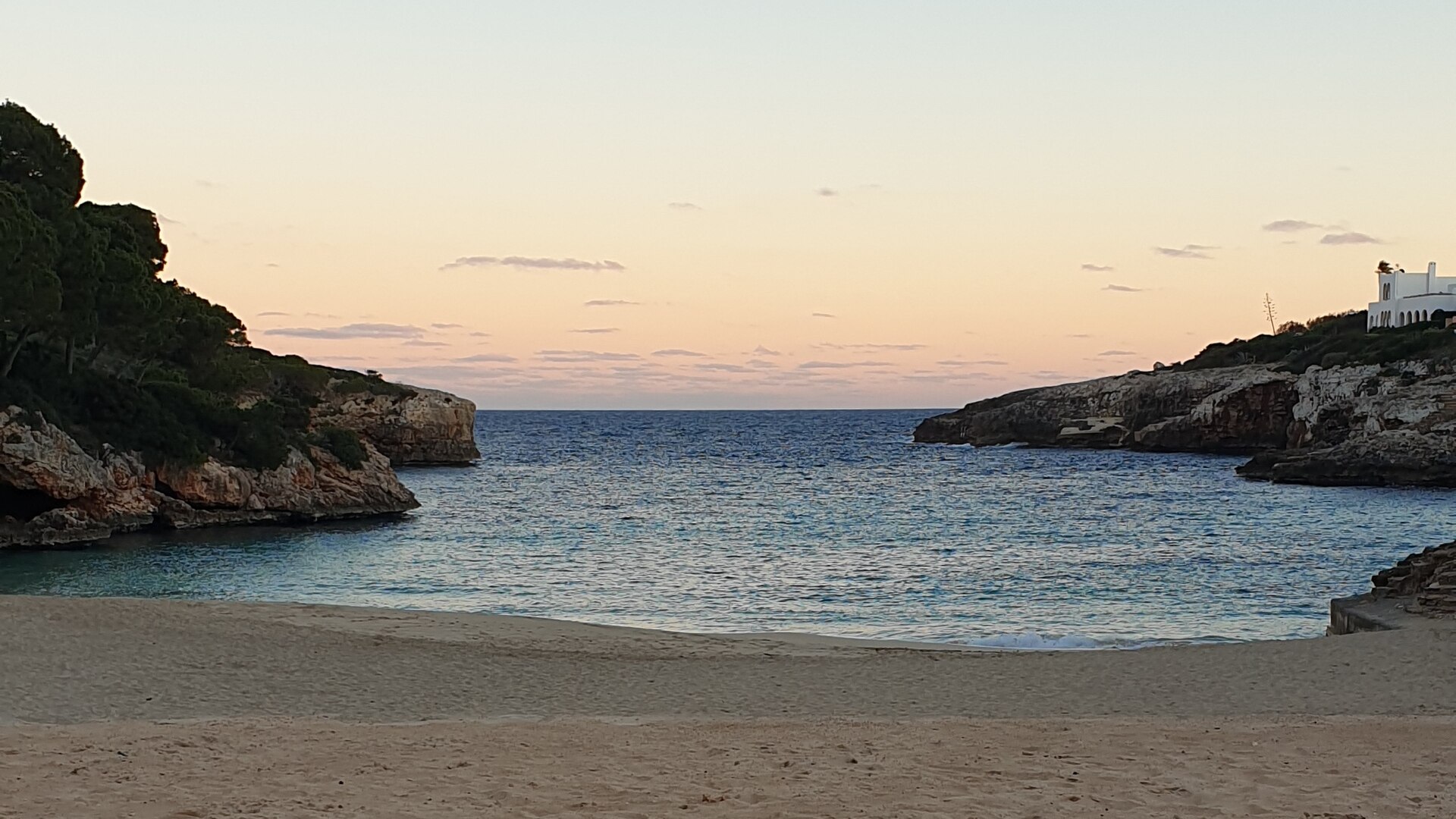 Cala Esmeralda in de schemering, met leeg zand op de voorgrond en de smalle baaimond tussen twee rotspunten