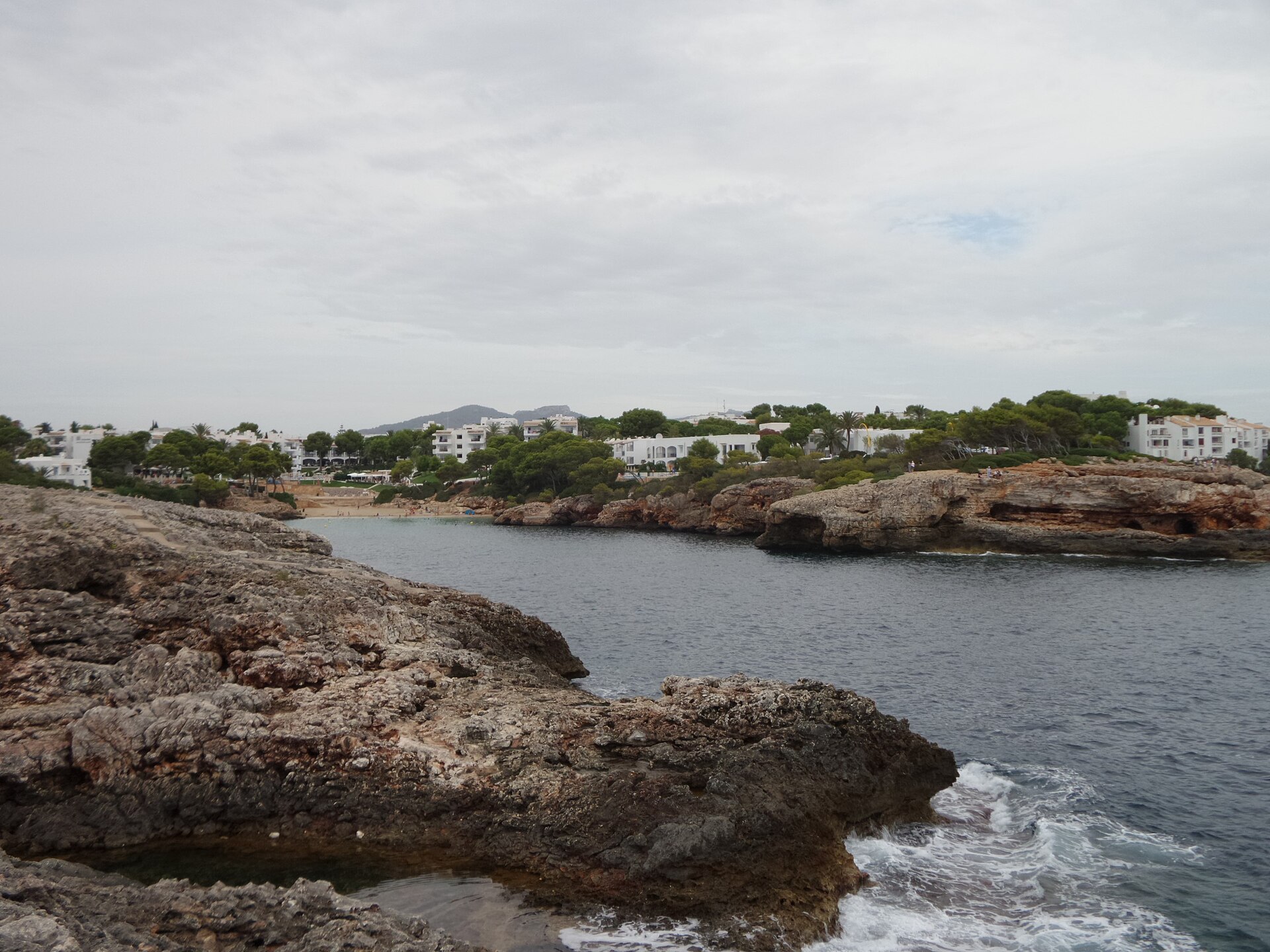 Cala Esmeralda gezien vanaf de rotspunt ernaast, met het strandje achterin en de witte bebouwing van Cala d'Or