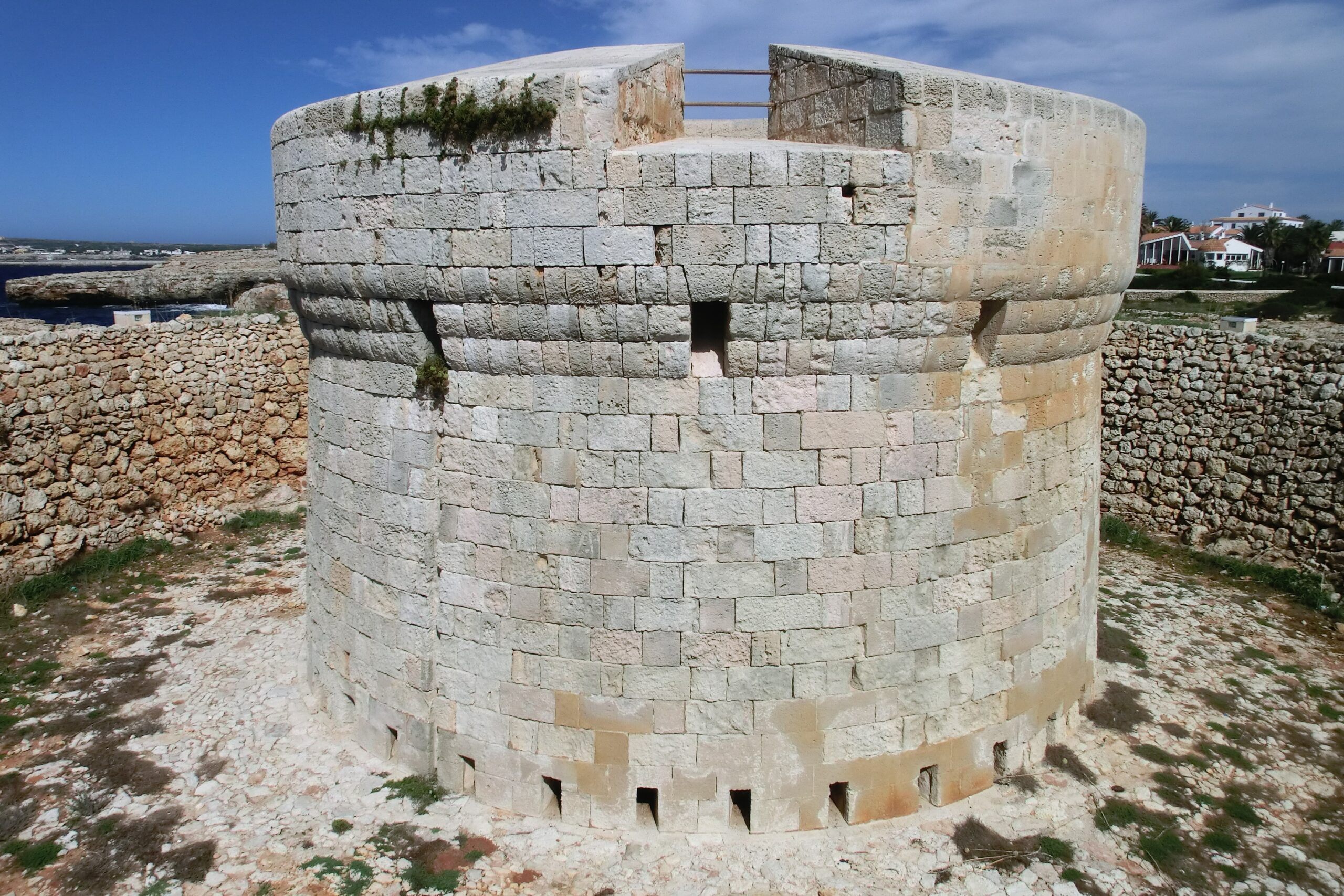 Cala Santandría Menorca: de beschutte kreek bij Ciutadella en de Torre des Castellar 2 De ronde Torre des Castellar bij Cala Santandría, opgetrokken uit blokken marès, met de schietgaten op de begane grond en de droge gracht eromheen