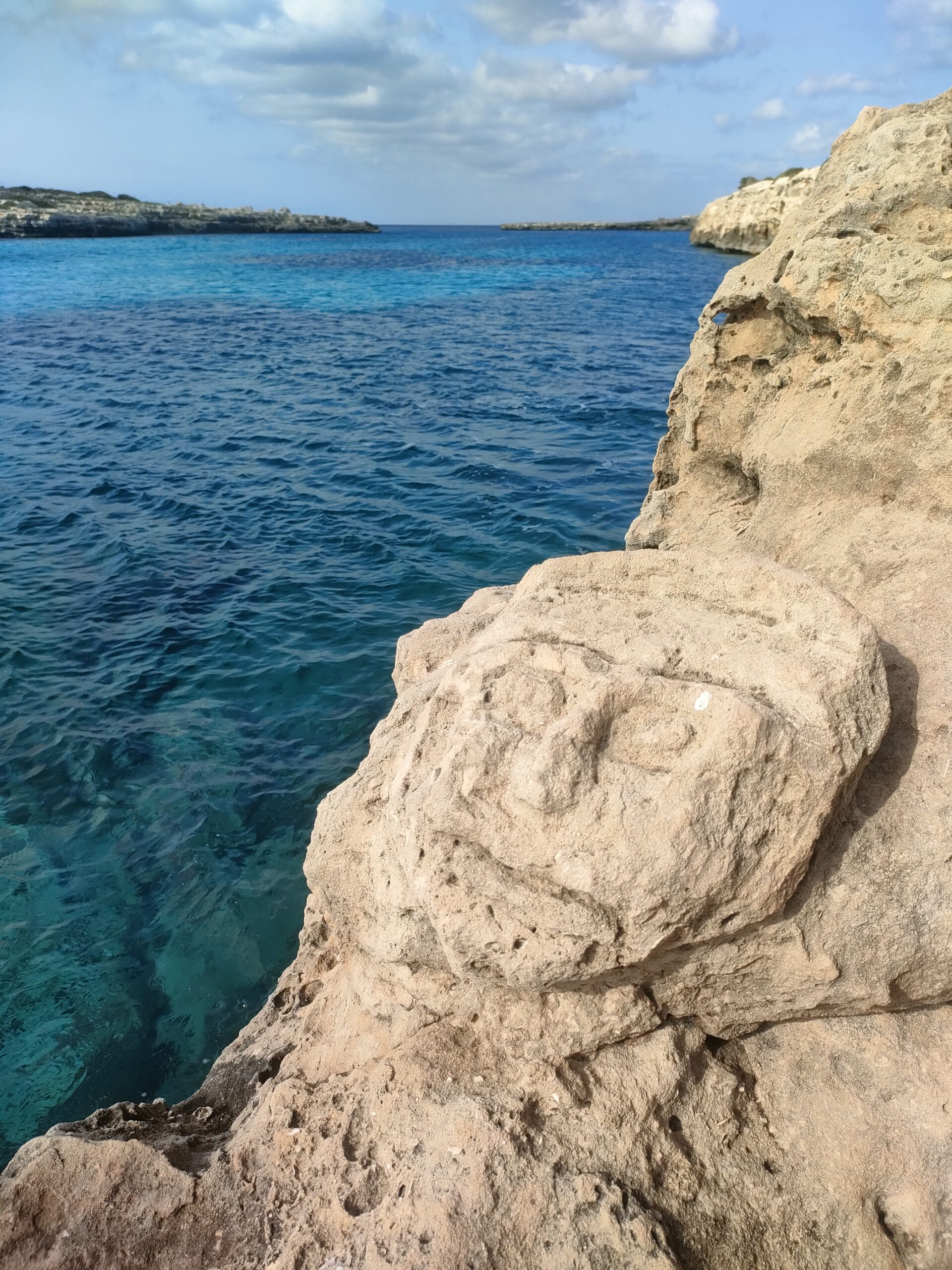Cala Santandría Menorca: de beschutte kreek bij Ciutadella en de Torre des Castellar 7 Een in de rots uitgehouwen gezicht bij Sa Cova de ses Tres Boques boven het blauwe water bij Cala Santandría