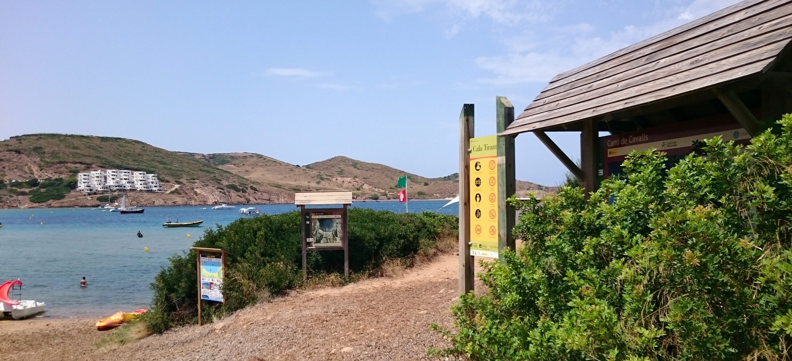 De toegang tot Cala Tirant met het informatiebord en de wegwijzer van het Camí de Cavalls