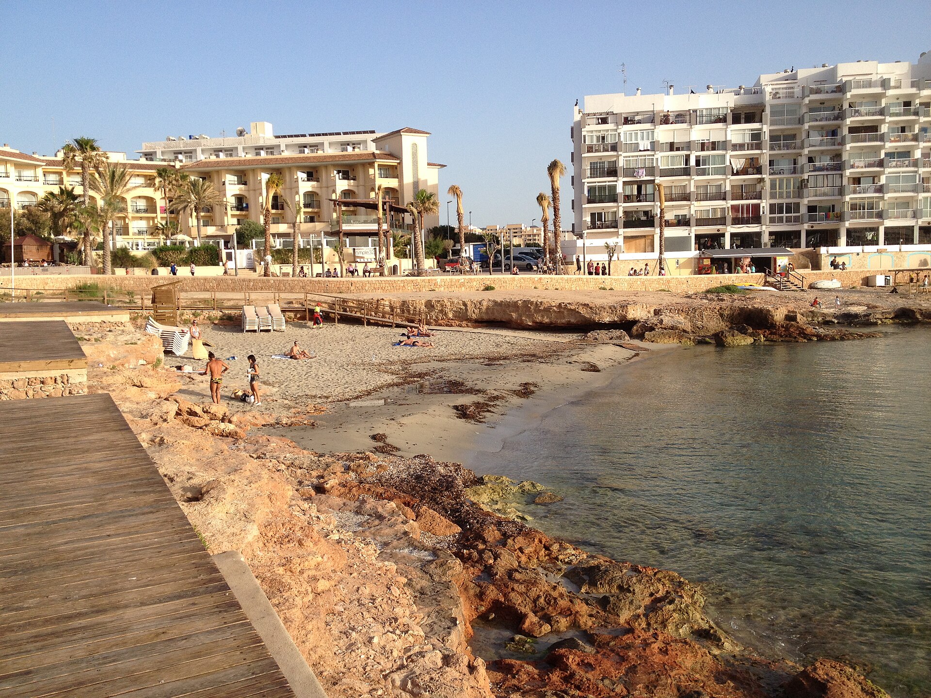 Caló des Moro Ibiza: het strandje aan de Sunset Strip van Sant Antoni 1 Het zandstrandje van Caló des Moro in Sant Antoni, met de houten vlonder langs de rotsen en de appartementen van de badplaats erachter