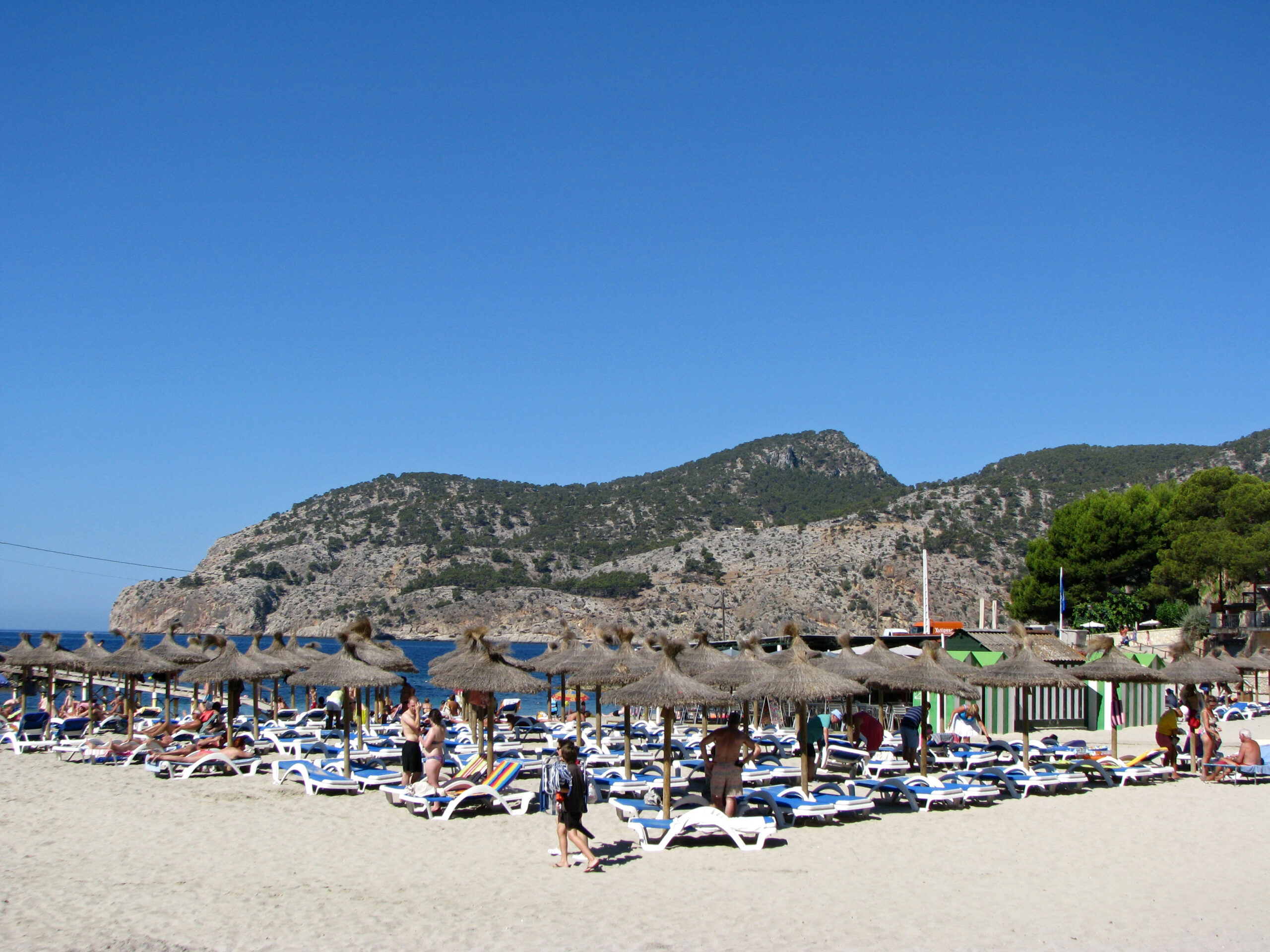 Camp de Mar Mallorca: chic familiestrand met het eiland-restaurant 4 Het strand van Camp de Mar met dichte rijen ligbedden onder strooien parasols en de kale bergrug aan de overkant van de baai
