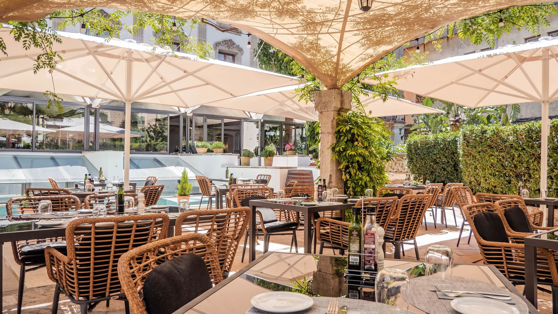 Ca'n Blau Sóller: het restaurant van het Gran Hotel uit 1880 9 Het tuinterras van Ca'n Blau in Sóller met rieten stoelen onder witte parasols tussen de bomen