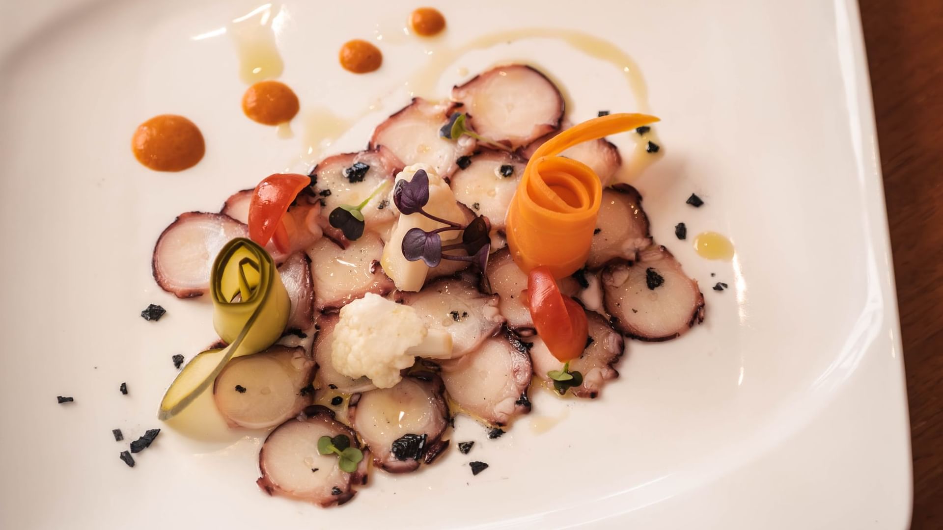 Ca'n Blau Sóller: het restaurant van het Gran Hotel uit 1880 4 Carpaccio van octopus met plakjes tomaat, olijfcrumble en gekleurde sauspunten op een wit bord