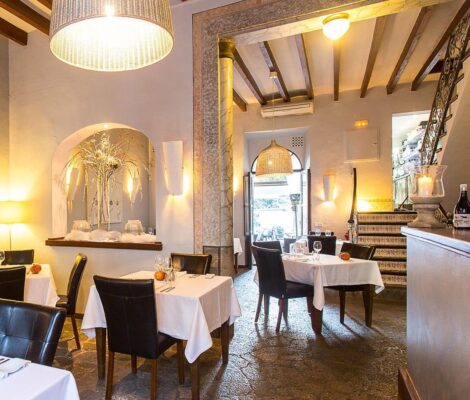 De eetzaal van restaurant Ca'n Boqueta in Sóller met witte tafellakens, houten balkenplafond, een stenen vloer en een trap met beschilderde tegels