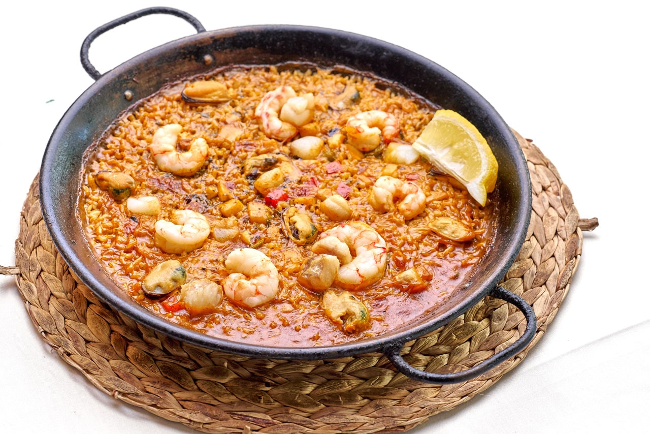 Paella met gamba's in een zwarte pan op een rieten onderzetter bij Ca n'Eduardo in Palma