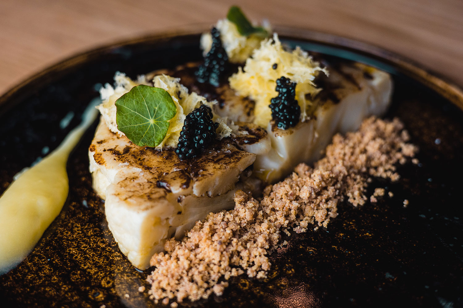Ca'n Pintxo Sóller: Baskische hapjes van Mallorcaanse grond 1 Gegrilde witte vis met kaviaar en een krokante korst op een donker bord bij Ca'n Pintxo in Sóller