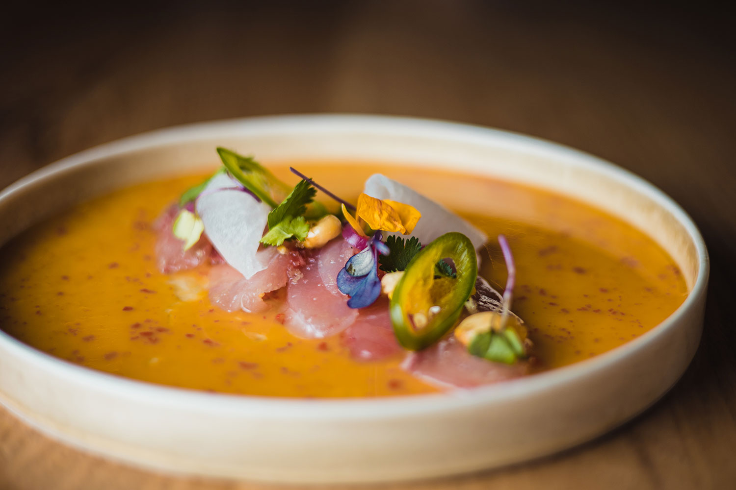 Ca'n Pintxo Sóller: Baskische hapjes van Mallorcaanse grond 2 Rauwe vis met eetbare bloemen in een gele saus op een wit bord bij Ca'n Pintxo in Sóller