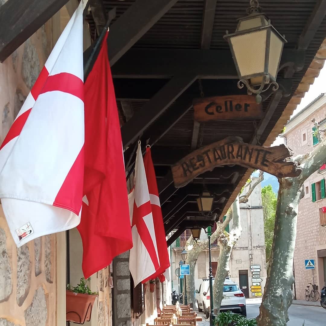 De gevel van Cas Carreter in Sóller met vlaggen en een houten bord waarin Celler Restaurante is uitgesneden