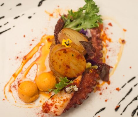 Cas Carreter Sóller: eten in het karrenhuis uit 1914 9 Gegrilde octopus met geroosterde aardappel en eetbare bloemen op een wit bord bij Cas Carreter in Sóller