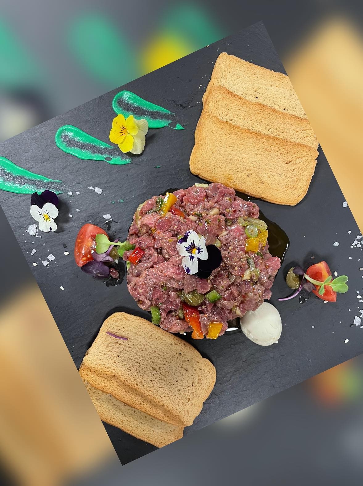 Tartaar van rund op een leisteen plaat met geroosterd brood en eetbare bloemen bij Cas Carreter in Sóller