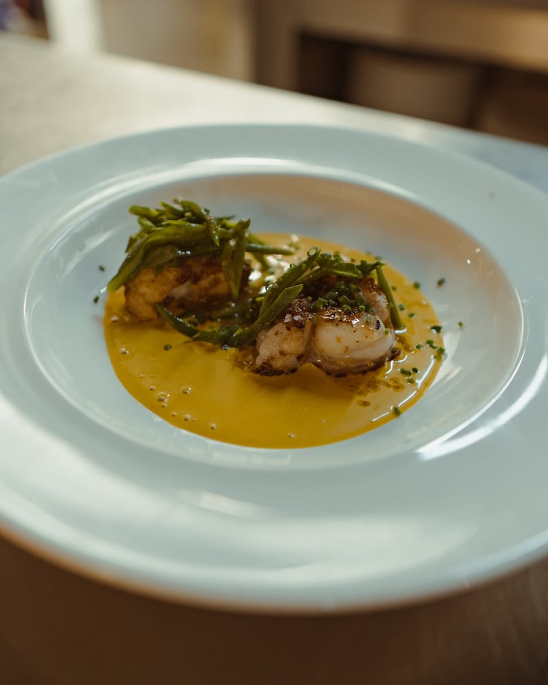 Casa Maruka in Palma: de casa de comidas met een Sol Repsol 8 Twee stukken gebakken vis met zeekraal in een gele saus op een lichtblauw bord bij Casa Maruka in Palma