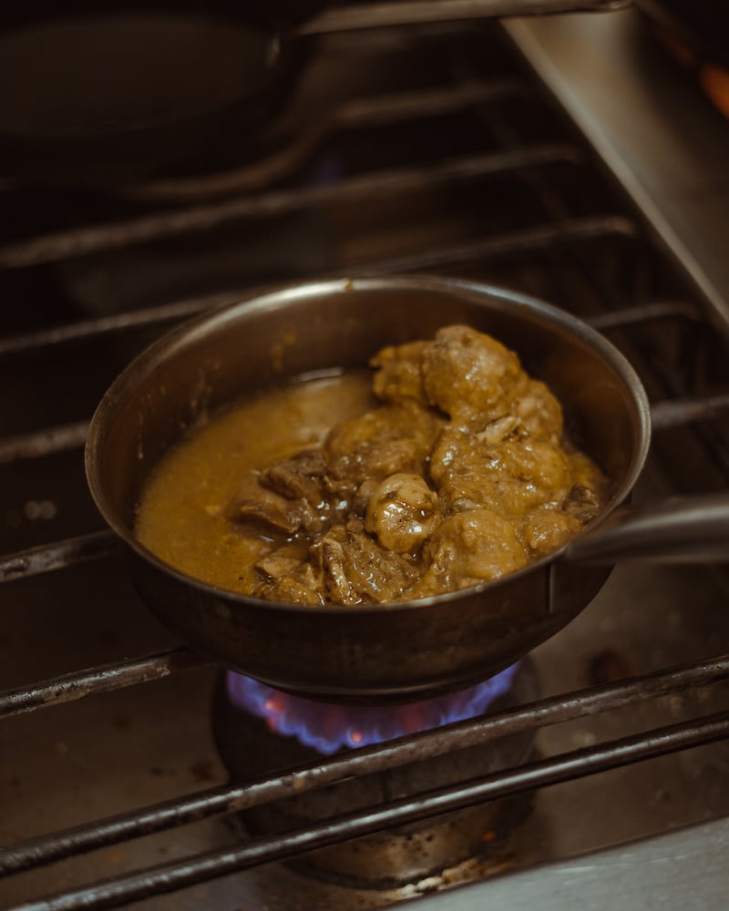 Casa Maruka in Palma: de casa de comidas met een Sol Repsol 6 Stoofpannetje met vlees in een dikke saus op de gasvlam in de keuken van Casa Maruka in Palma