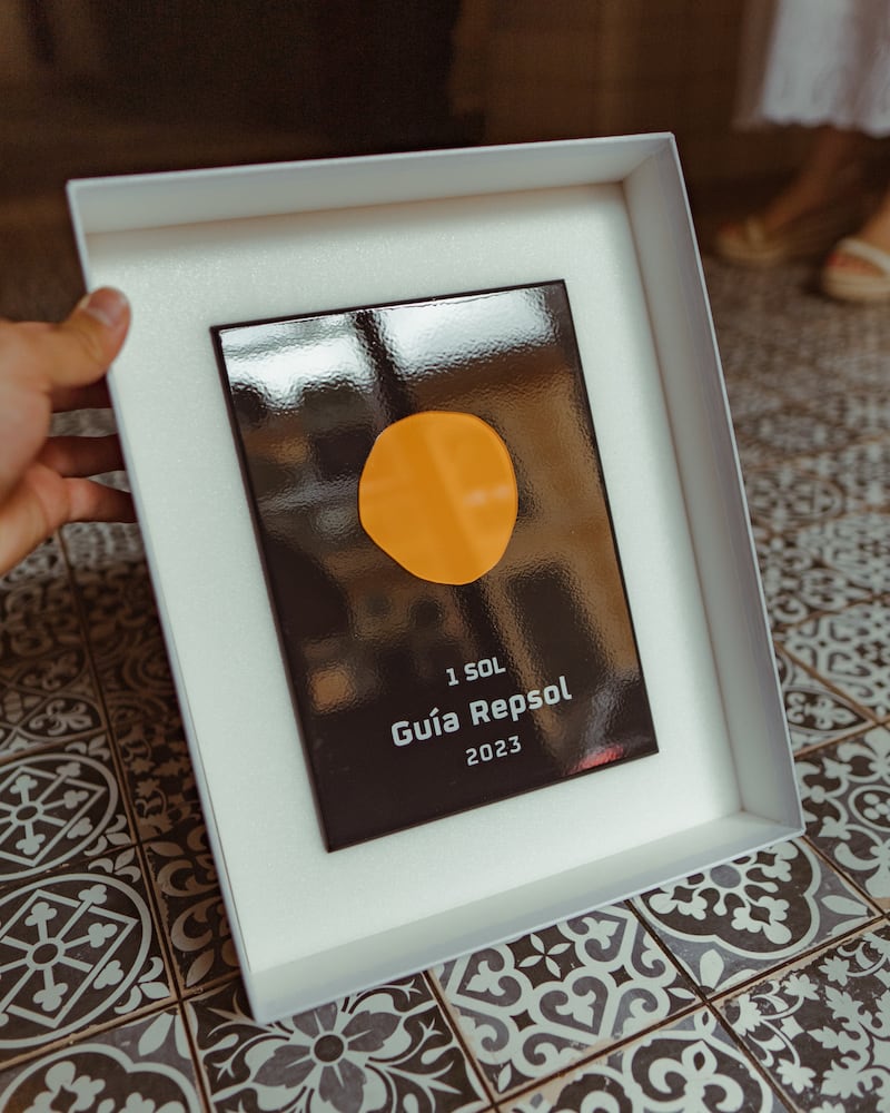 Casa Maruka in Palma: de casa de comidas met een Sol Repsol 7 De ingelijste plaquette van één Sol Guía Repsol 2023 van Casa Maruka, boven de hydraulische tegelvloer van het restaurant