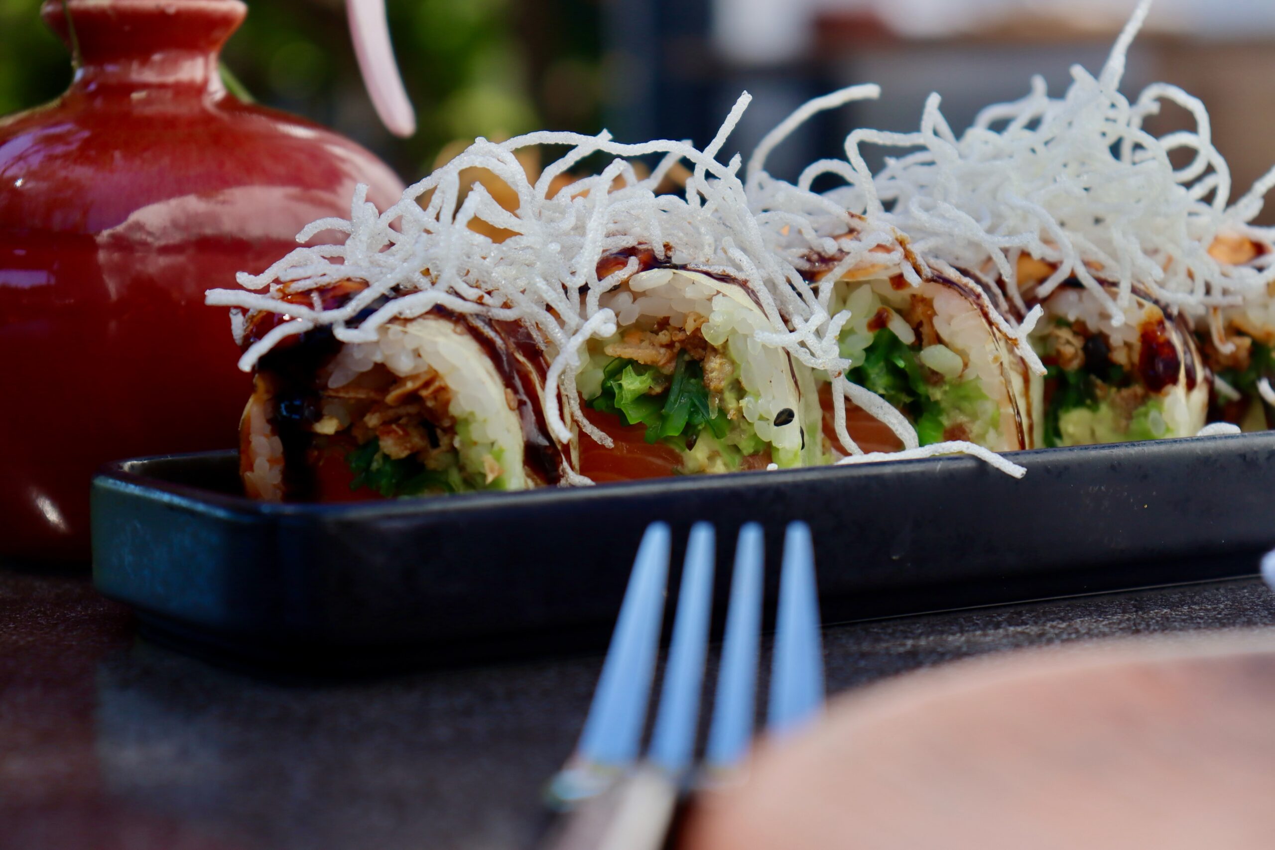 Uramaki met zalm, avocado en krokante mihoen op een zwart bord bij Casa Piedra op Ibiza