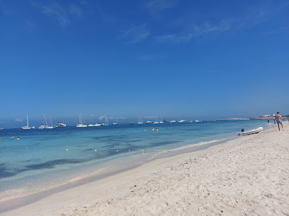 Het witte zand van Cavall d’en Borràs op Formentera met ondiep turquoise water en zeilboten voor anker
