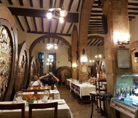 Het interieur van het oude Celler Can Amer in Inca met reusachtige houten wijnvaten langs de muren, stenen bogen, een balkenplafond en gedekte tafels