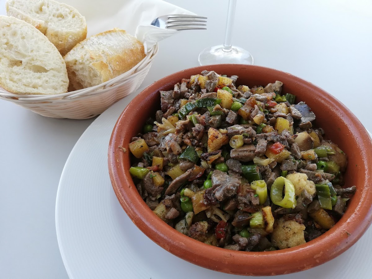 De verdwijnende cellers van Mallorca: het pand is beschermd, de zaak niet 4 Een aarden schaal met frit van vlees, aardappel, paprika en peultjes met een mandje wit brood ernaast