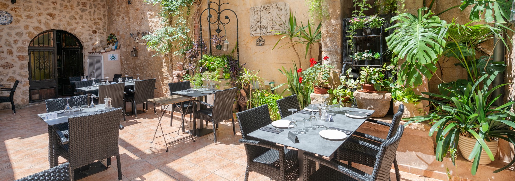 De verdwijnende cellers van Mallorca: het pand is beschermd, de zaak niet 2 De beschutte binnenplaats van Celler Ca'n Costa in Alcudia met gedekte tafels tussen potplanten langs een natuurstenen muur