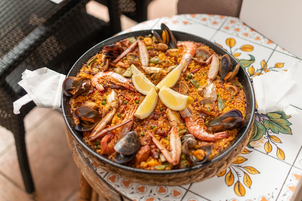 Celler Ca'n Costa in Alcúdia: Mallorquijnse keuken in een huis uit 1594 2 Paella met gamba's, mosselen en schelpdieren in een ijzeren pan op een handbeschilderde tegeltafel van Celler Ca'n Costa in Alcúdia