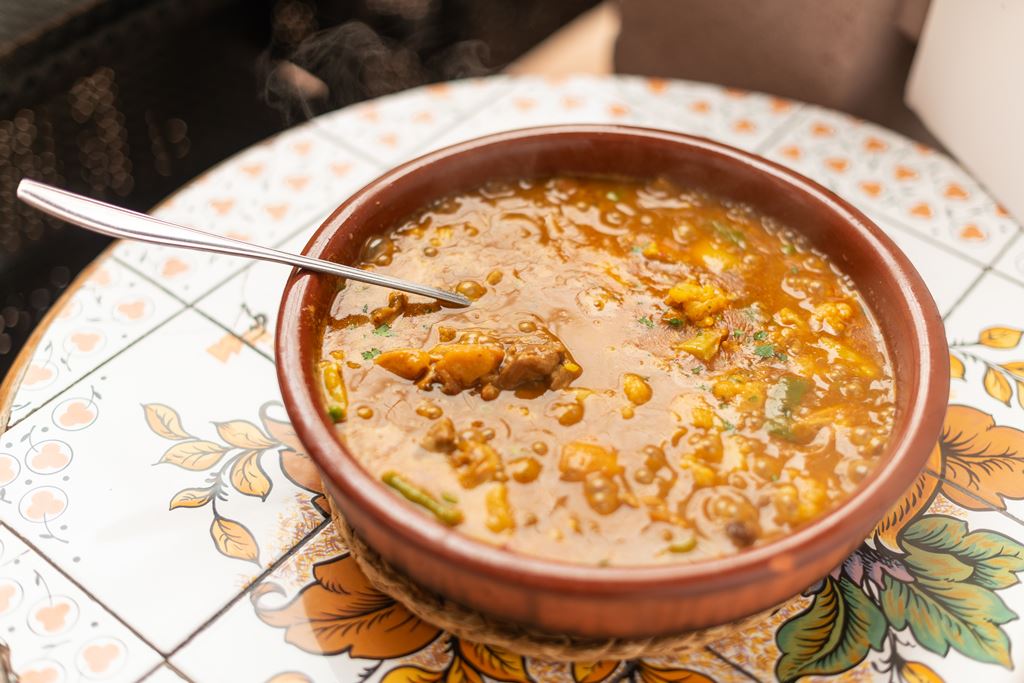 De verdwijnende cellers van Mallorca: het pand is beschermd, de zaak niet 5 Een aardewerken schaal met natte rijst in bouillon met een lepel erin op een beschilderde tegeltafel