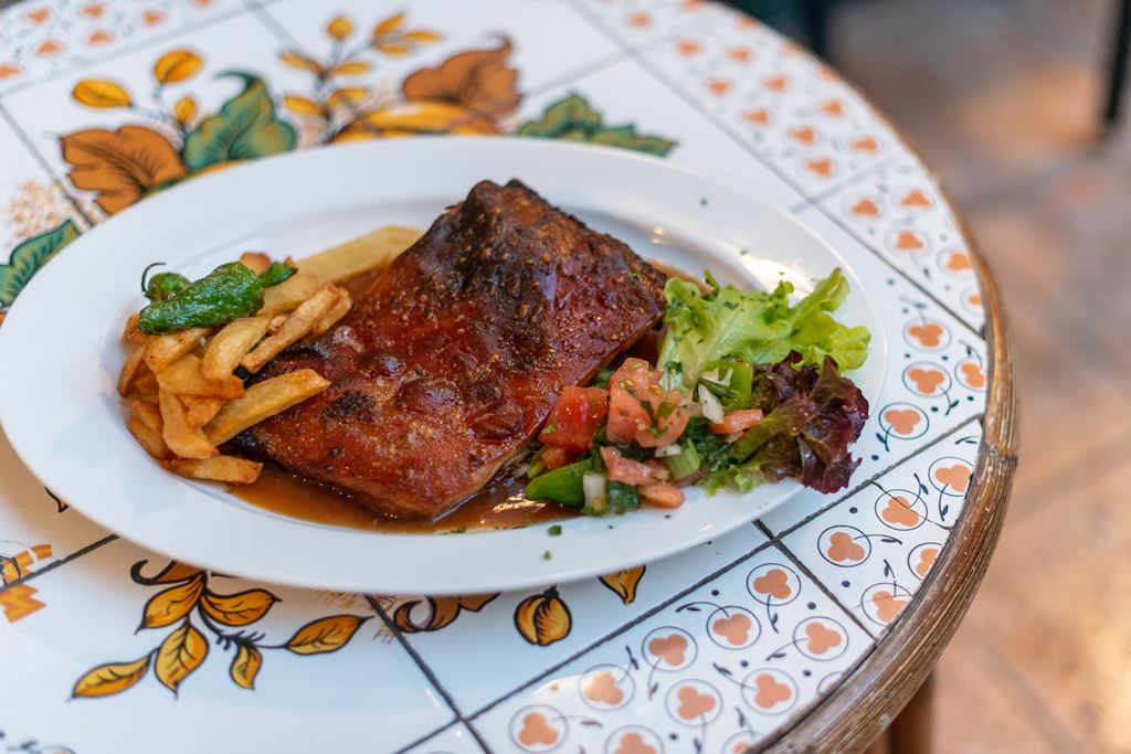 Celler Ca'n Costa in Alcúdia: Mallorquijnse keuken in een huis uit 1594 5 Een stuk geroosterd vlees met krokante korst, friet en salade op een wit bord van Celler Ca'n Costa