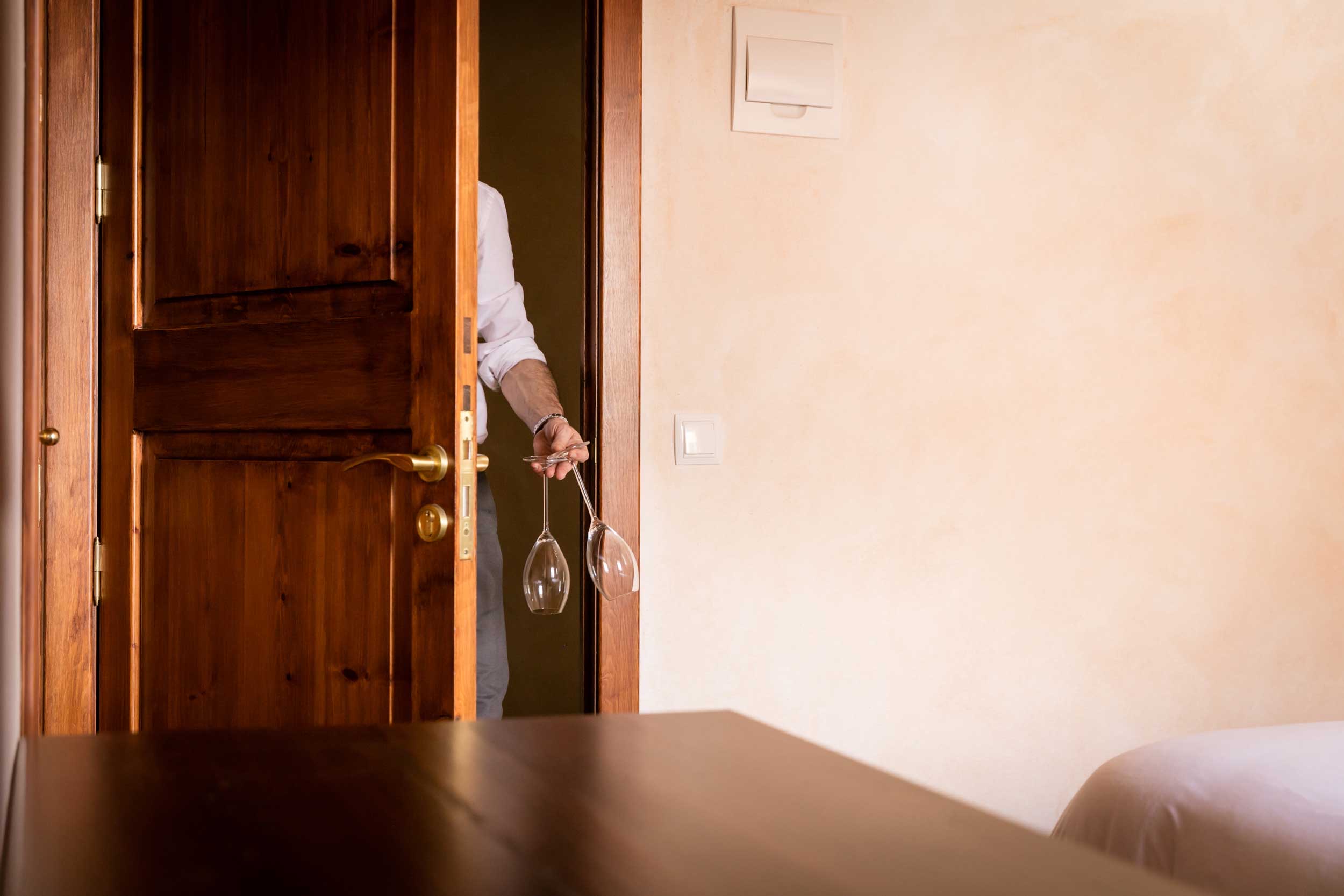 DaiCa in Llubí: dorpsrestaurant met Sol Repsol en drie kamers 2 Een ober komt met twee wijnglazen door de houten deur van het oude dorpshuis van DaiCa in Llubí