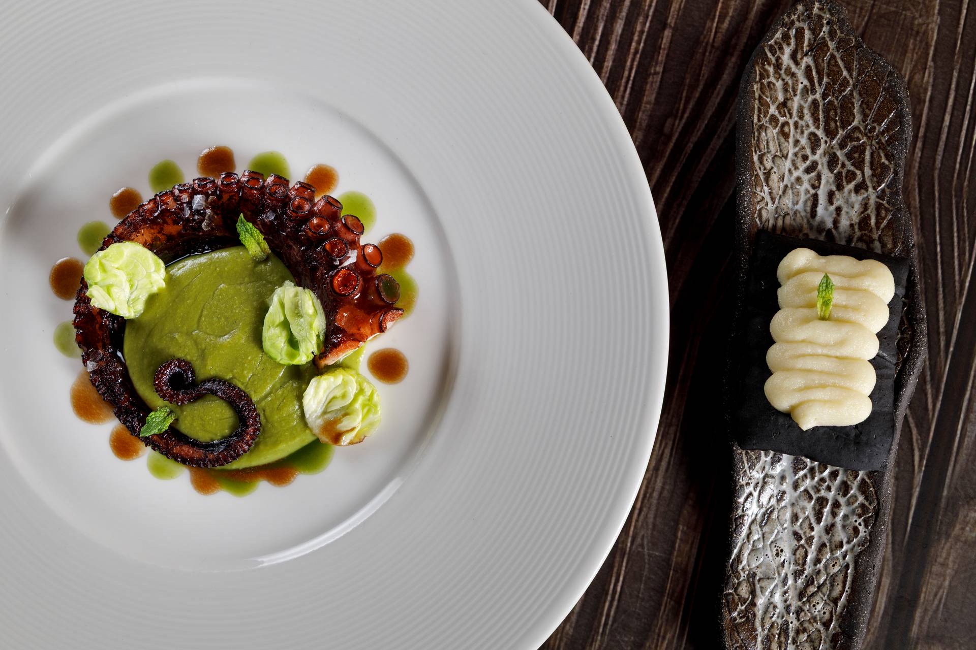 DaiCa in Llubí: dorpsrestaurant met Sol Repsol en drie kamers 4 Gegrilde octopus op een groene erwtencrème naast een zwarte cracker met aardappelpuree