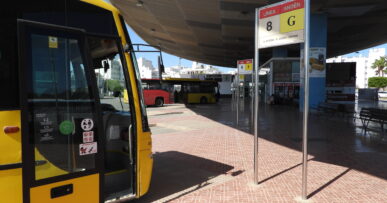 Gele bussen onder de overkapping van het busstation van Sant Antoni de Portmany op Ibiza, met een bord met lijn- en perronnummer