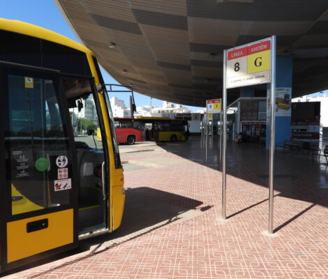 Gele bussen onder de overkapping van het busstation van Sant Antoni de Portmany op Ibiza, met een bord met lijn- en perronnummer