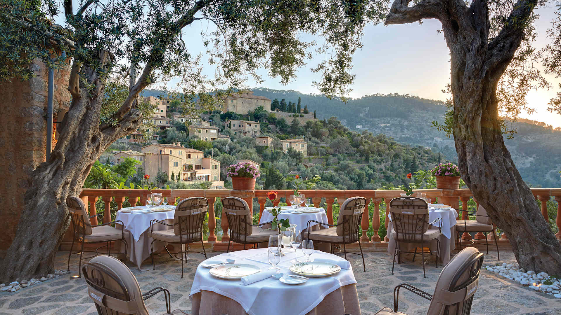 Het terras van restaurant El Olivo in Deia met gedekte tafels onder oude olijfbomen en uitzicht op het dorp en de Tramuntana