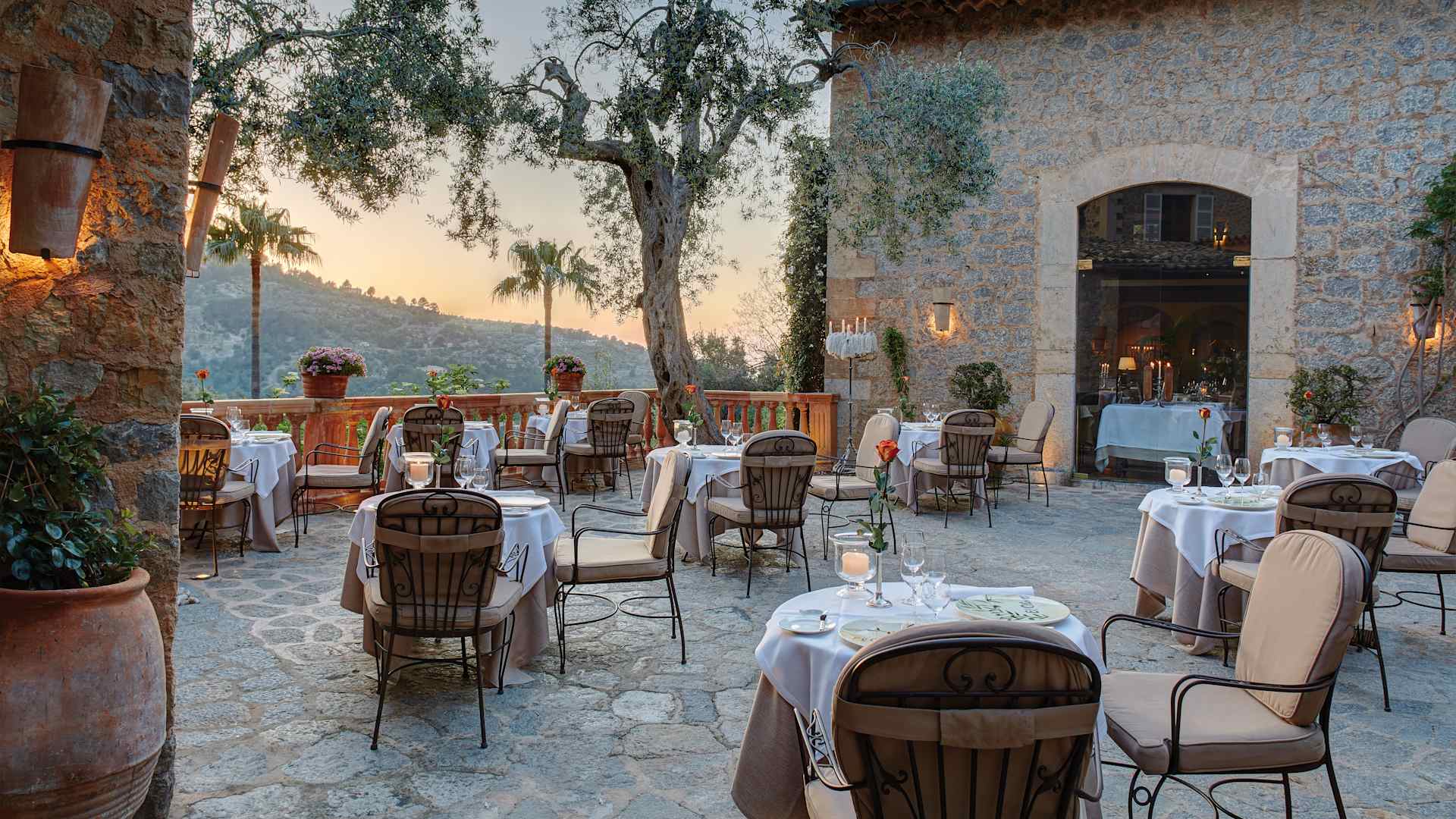 Het terras van El Olivo in de schemering, met kaarsen op de tafels en de verlichte gevel van de oude molen