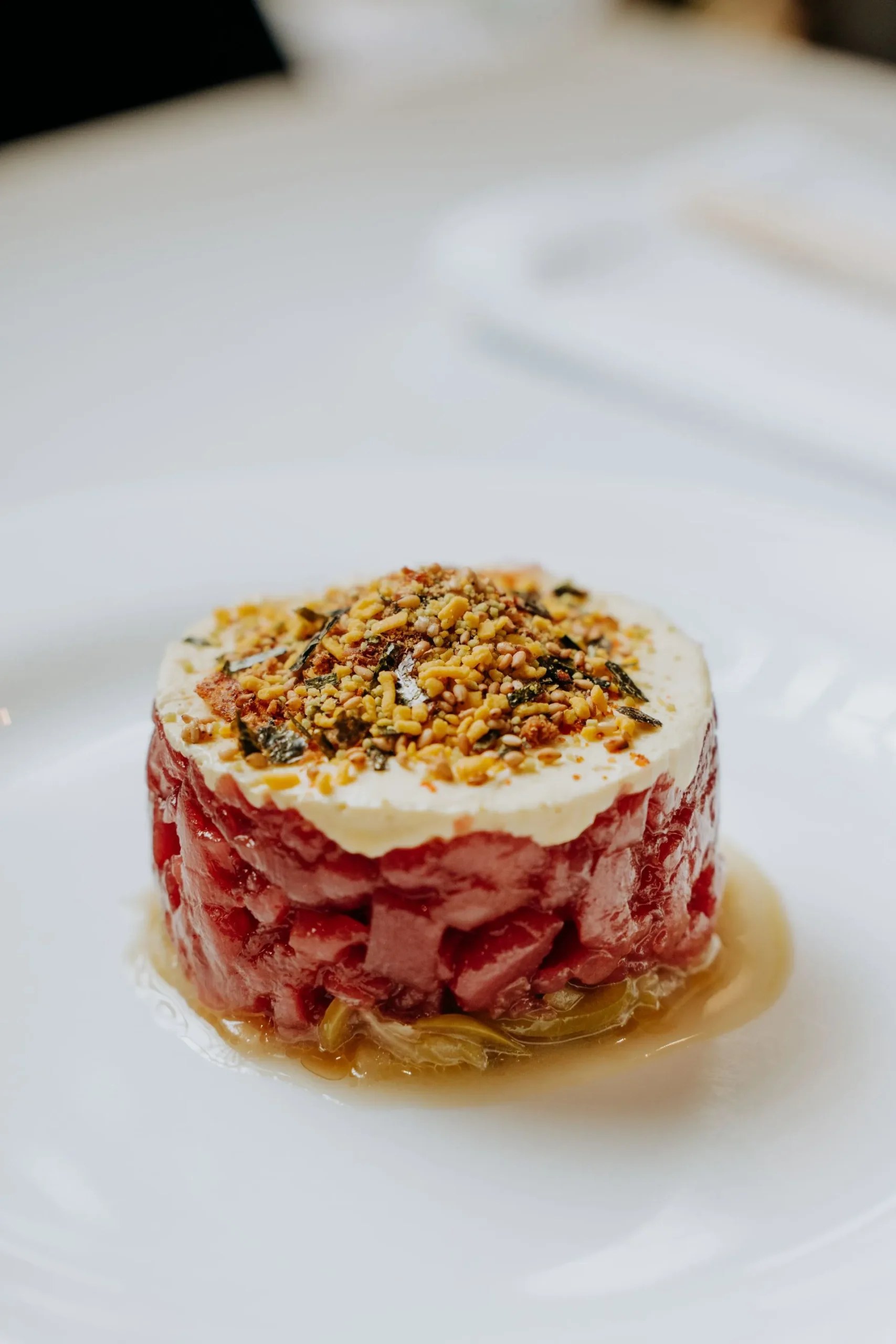 Emilio Innobar in Palma: fine fusion van Japan, Mexico en Mallorca 3 Tartaar van rauwe vis in een ronde vorm met een laagje room en gehakte noten, op een wit bord bij Emilio Innobar in Palma