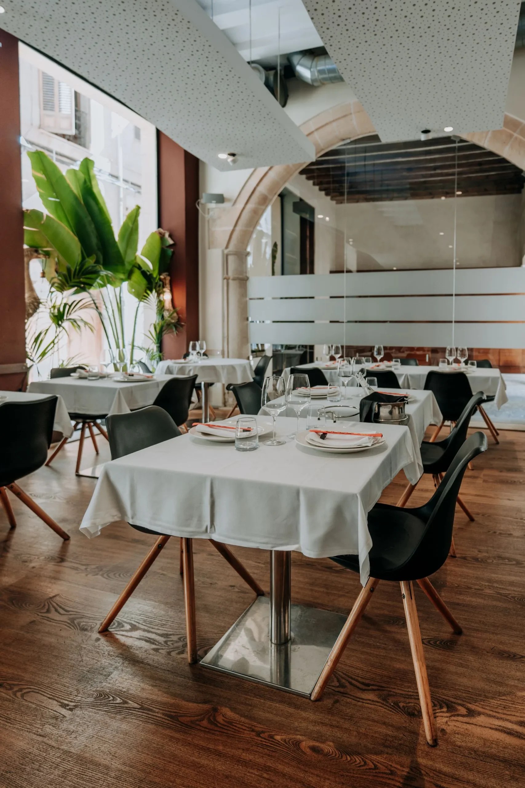 Emilio Innobar in Palma: fine fusion van Japan, Mexico en Mallorca 6 Tweede eetzaal van Emilio Innobar in Palma met houten vloer, gedekte tafels en een stenen boog met daglicht en planten