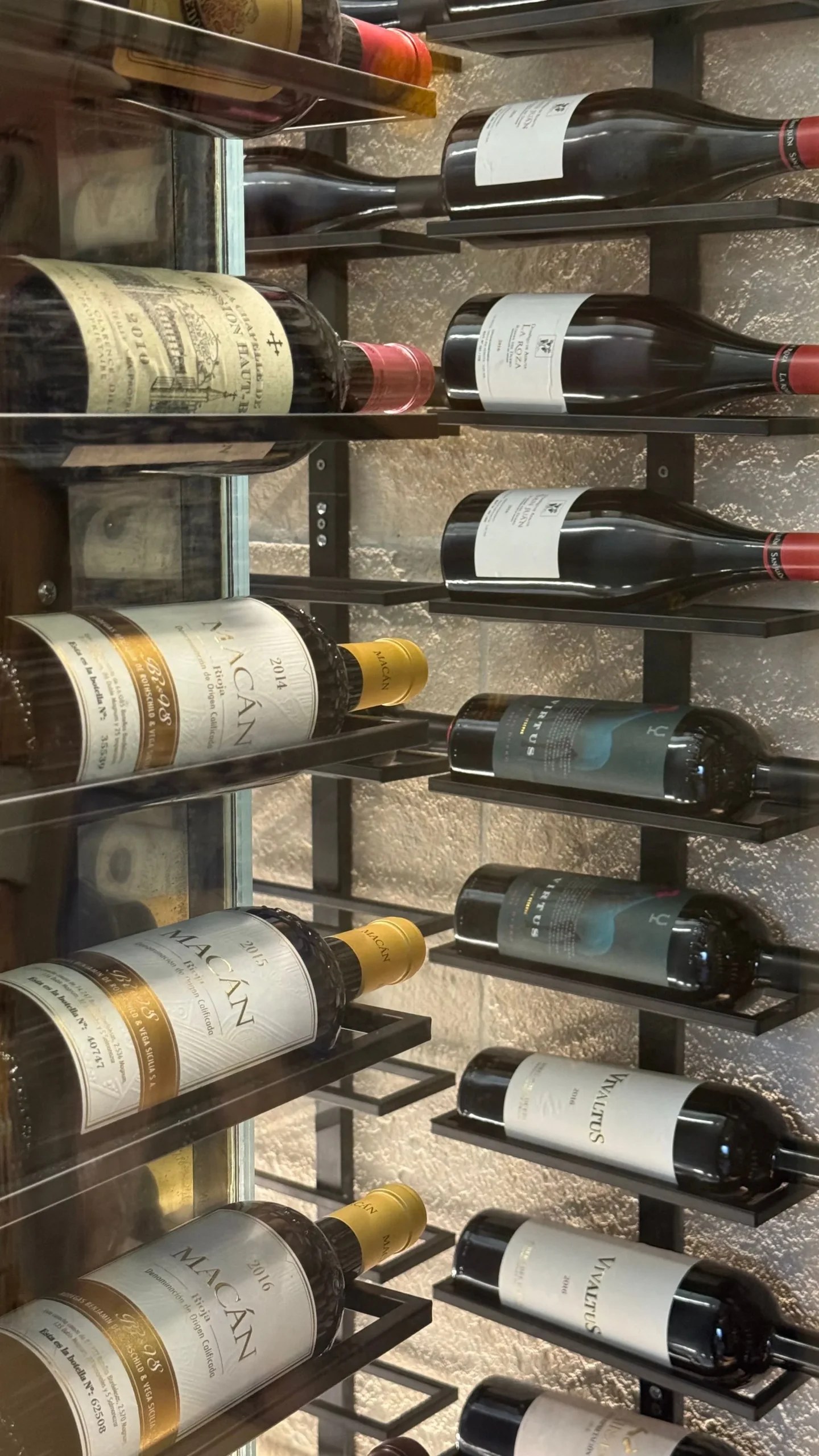 Emilio Innobar in Palma: fine fusion van Japan, Mexico en Mallorca 7 Wijnflessen liggend in een metalen rek tegen een natuurstenen muur in het restaurant van Emilio Innobar in Palma